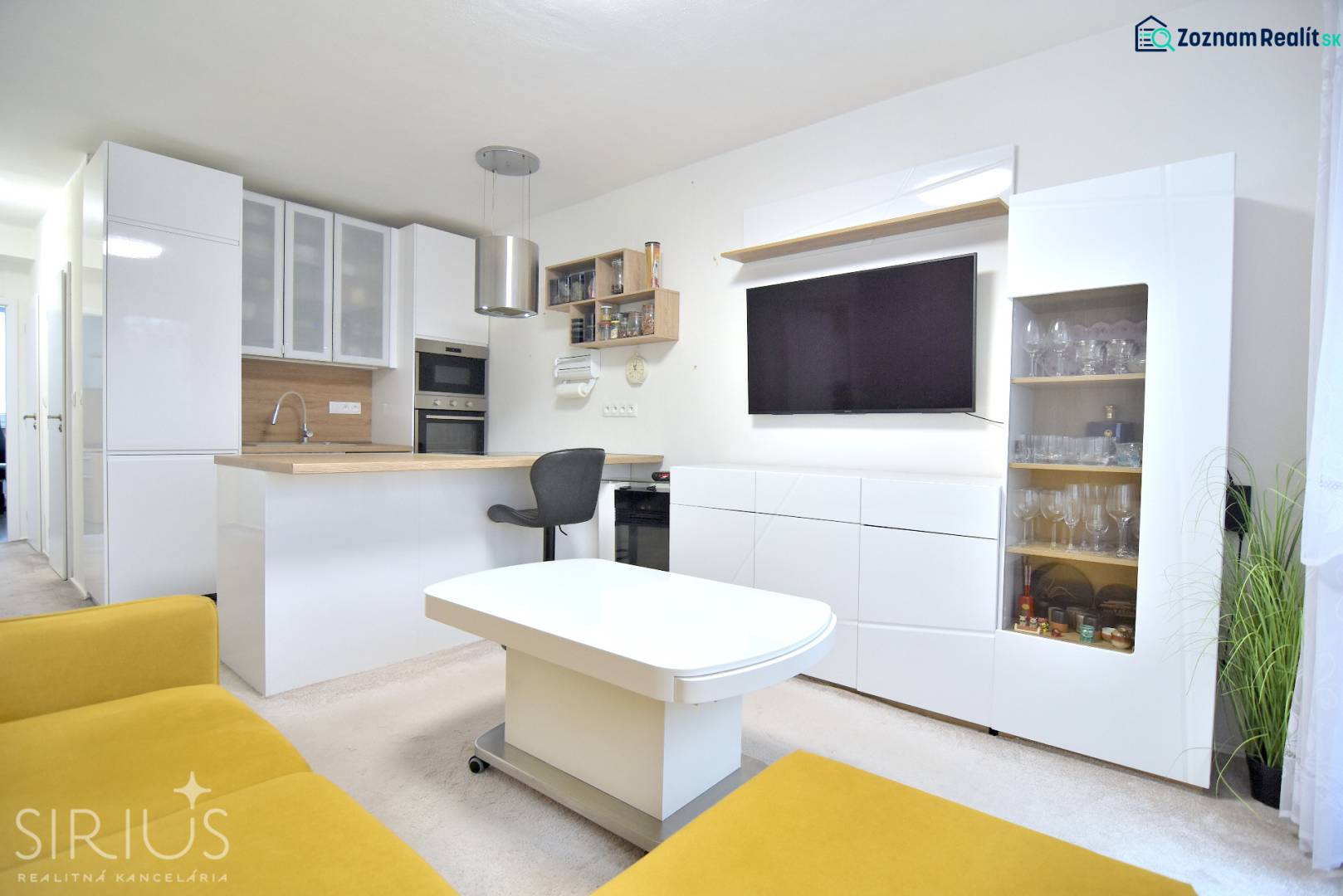 ŠTÚROVA, 3-i byt, 75 m2 – komplet rekonštrukcia, vlastné parkovanie - Obývacia izba s kuchyňou v 3-izbovom byte, biela nábytok, žltá sedačka, televízor.