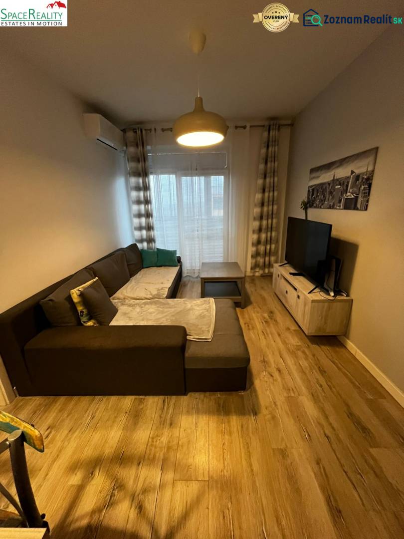 Predáme 2 izb byt v novostavbe v Senci  - Obývačka v 2-izbovom byte s pohodlnou sedačkou a podlahou s dreveným dekorom.