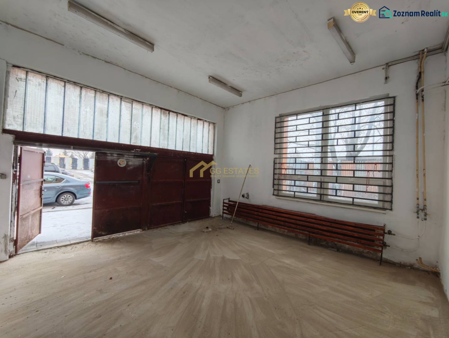 Prenájom Garáže na Hviezdoslavovej ulici. - Interiér garáže s podlahou s dreveným dekorom a kovovou bránou.