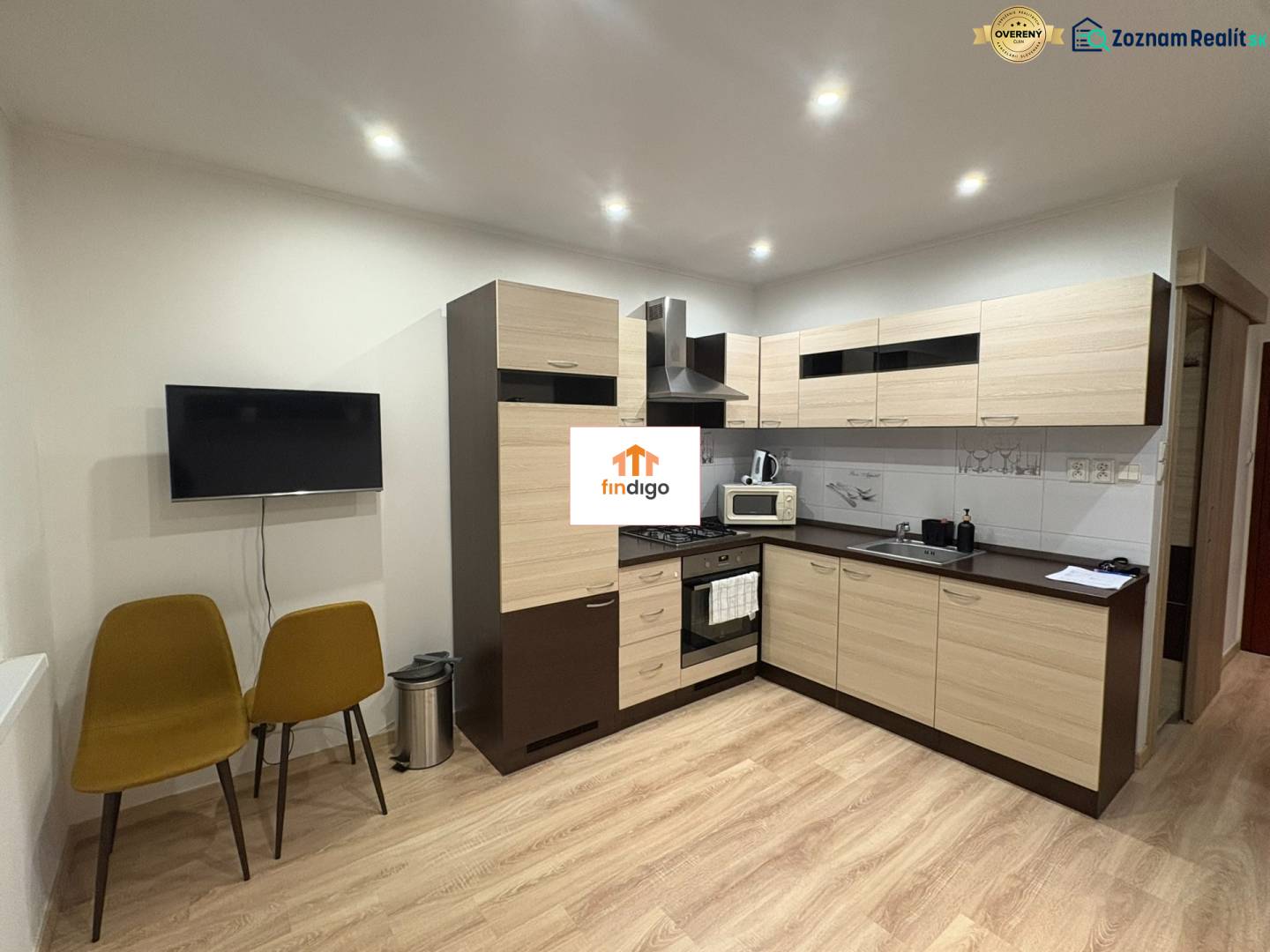 PRENÁJOM – 1-izbový byt po kompletnej rekonštrukcii, Šaľa – Bottova  - Kuchyňa v 1-izbovom byte s podlahou s dreveným dekorom a dvoma stoličkami.