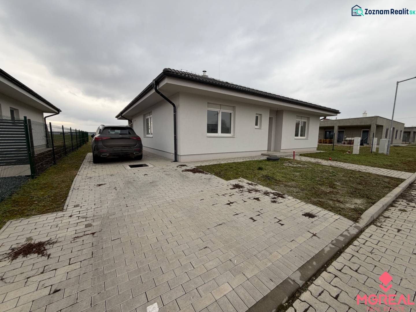 Novostavba rodinný dom Práznovce - Rodinný dom na ulici ticha v Práznovciach s automobilom na dláždenej príjazdovej ceste.