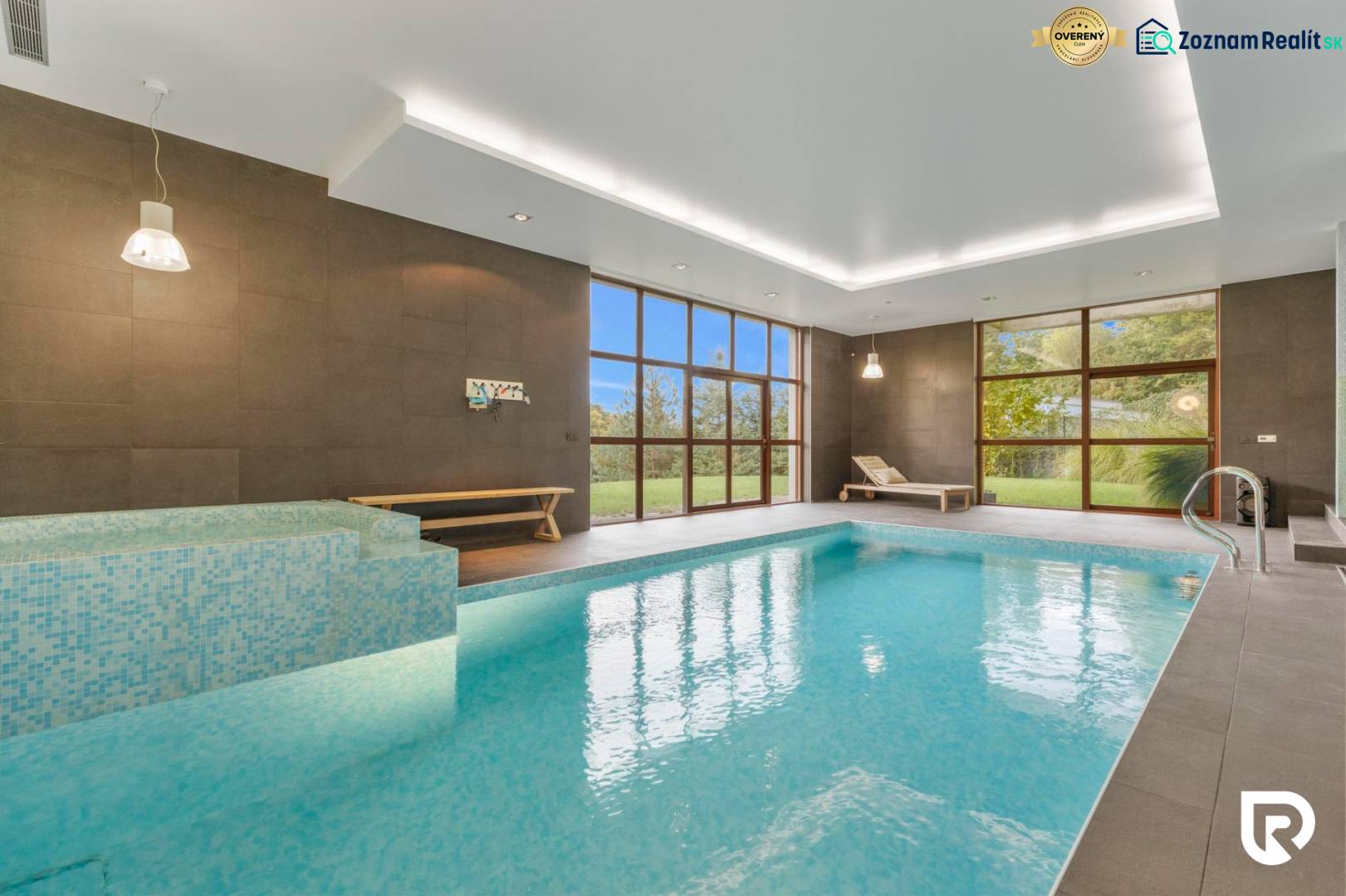 Nadštandardná 6-izbová vila v prominentnej lokalite - Vnútorný bazén vo vile s veľkými oknami, drevenými lavicami a zeleným výhľadom.
