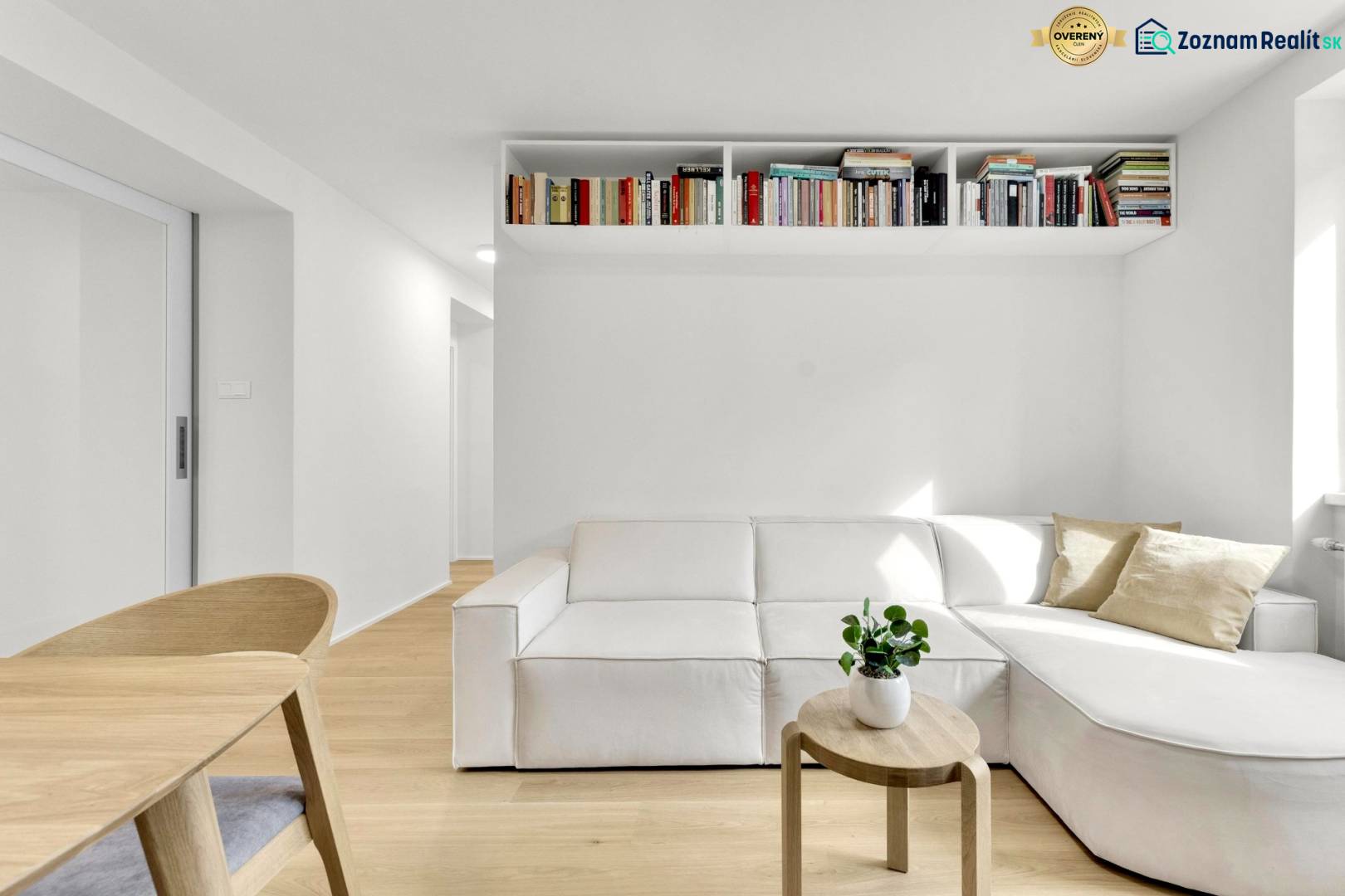 I Na predaj zrekonštruovaný 4i byt v Ružinove, Miletičova - Obývacia izba s bielou pohovkou, dreveným stolíkom a poličkou plnou kníh v 4-izbovom byte.