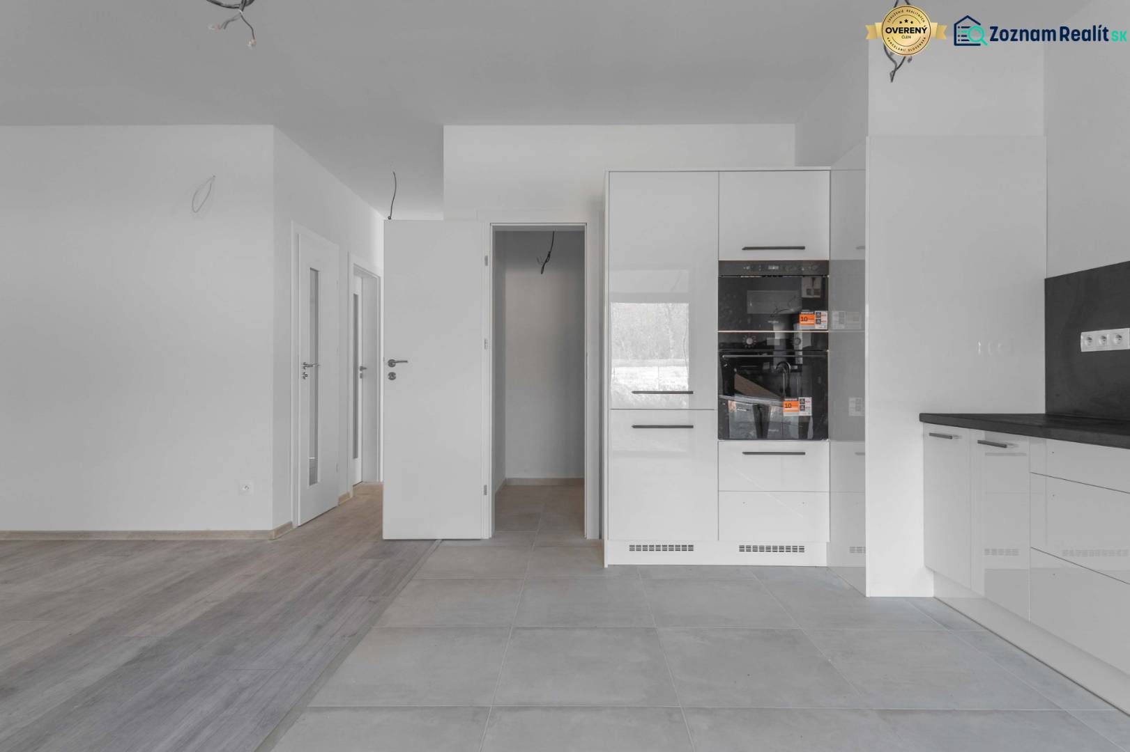 I PREDAJ novostavba 4i rodinného domu s terasou a záhradkou - Kuchyňa v rodinnom dome s bielou kuchynskou linkou a podlahou s dreveným dekorom.