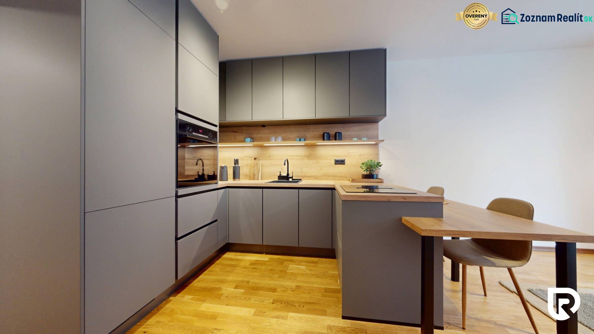 METROPOLIS I Nový Luxusný 2i byt s predzáhradkou I - Kuchyňa v 2-izbovom byte s podlahou s dreveným dekorom, šedými skrinkami a jedálenským stolom.