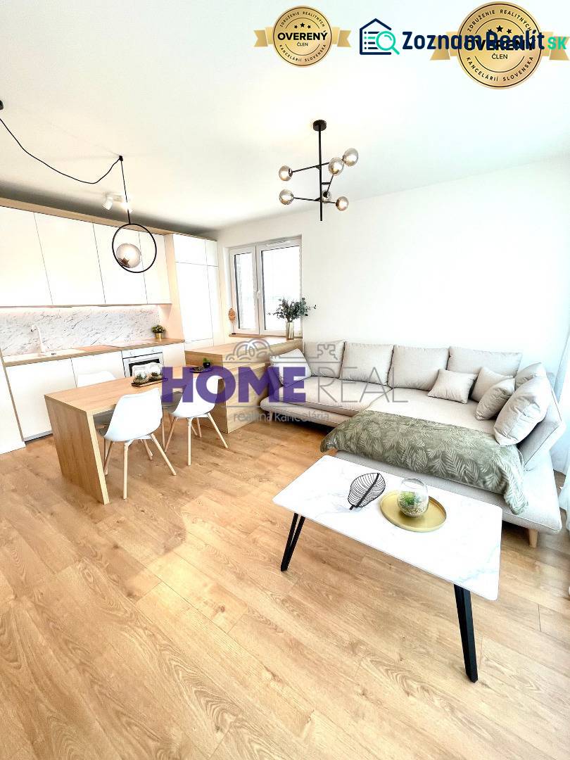 MODERNE A PRAKTICKY ZARIADENÝ 3 IZB. BYT V NOVOSTAVBE NA BOROCH. - Obývacia izba s kuchyňou v 3-izbovom byte, svetlá sedačka, podlaha s dreveným dekorom.