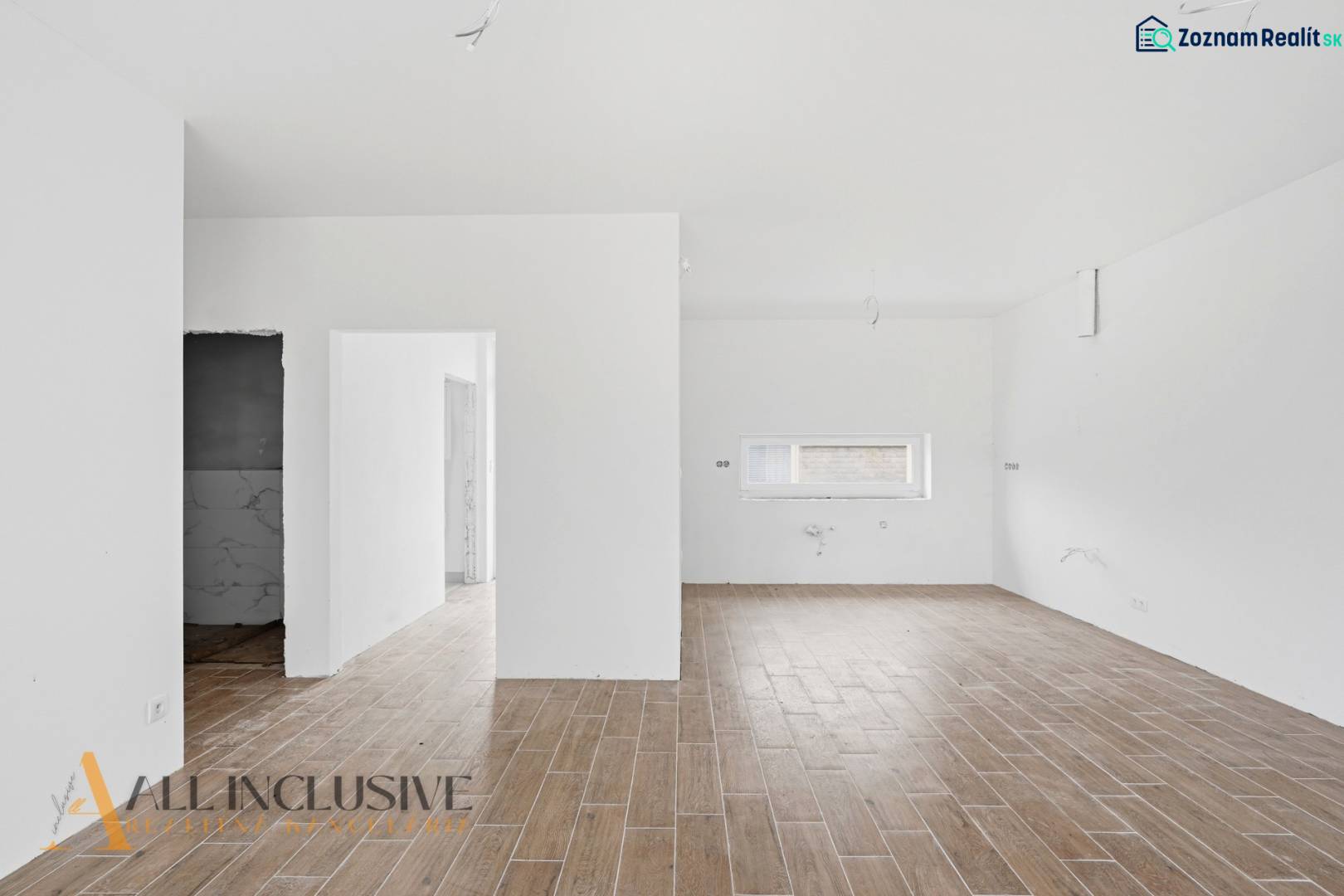 Na predaj 4-izbové novostavby, Veľká Paka - Interiér rodinného domu s podlahou s dreveným dekorom a bielymi stenami.