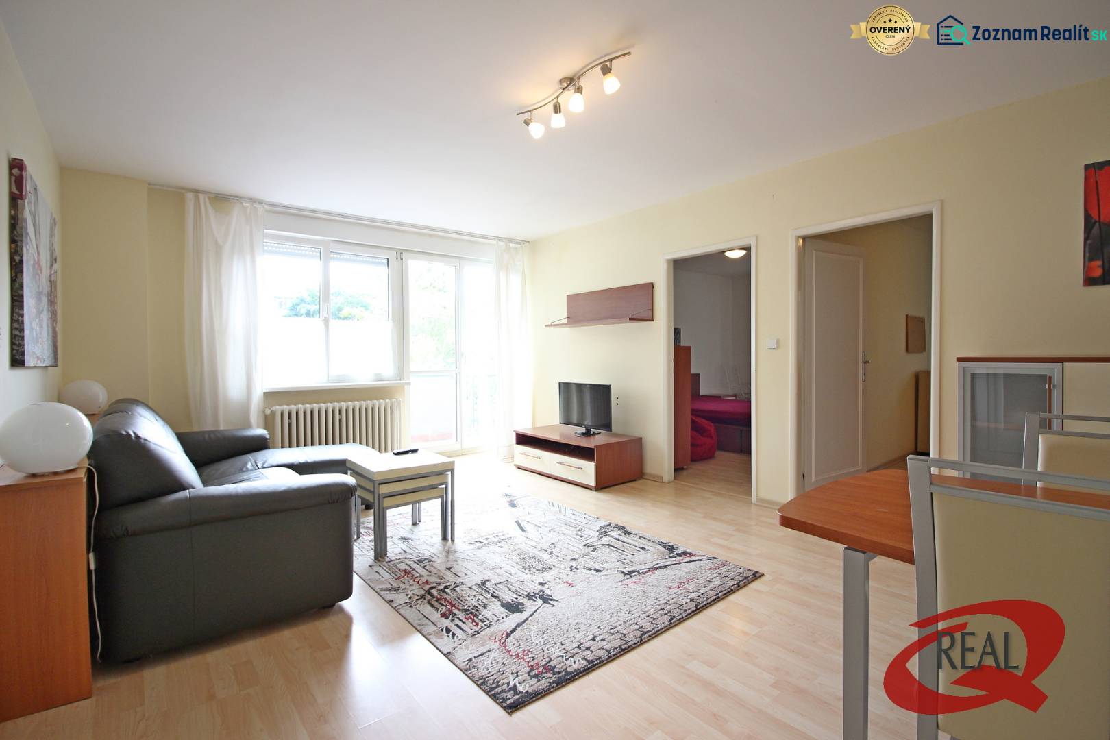 **BEZ PROVÍZIE**3-IZBOVÝ BYT S BALKÓNOM A LOGGIOU NA PALISÁDACH**      - Obývačka 3-izbového bytu s pohovkou, stolíkom a televíziou na podlahe s dreveným dekorom.