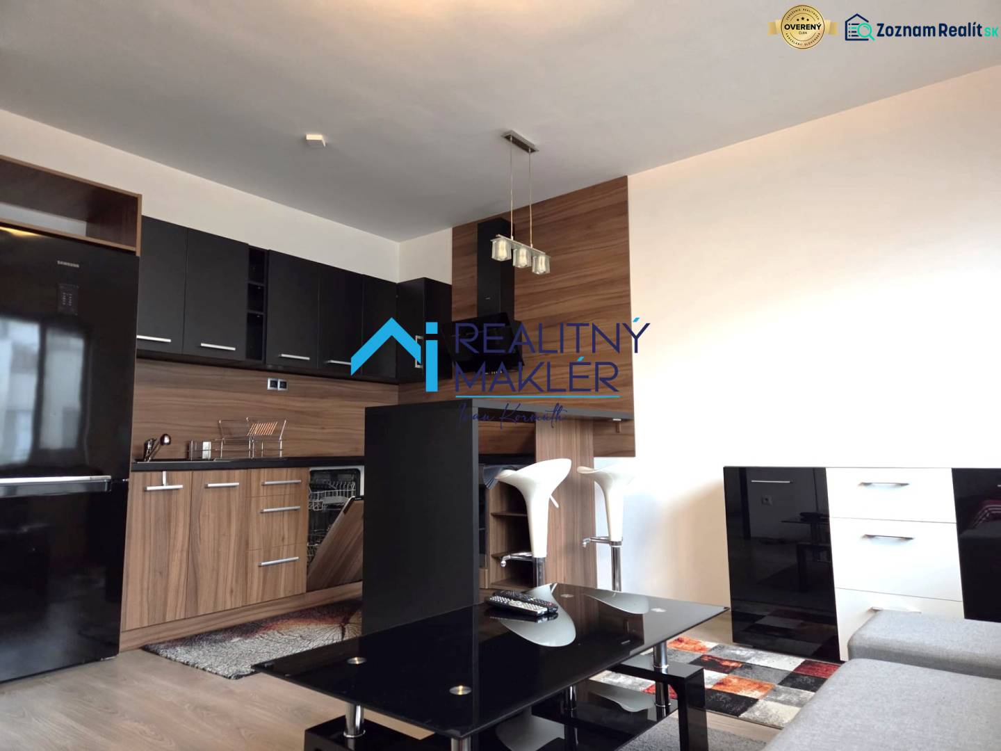 Prenajaté - 2.izbový byt s parkovaním v obci Hviezdoslavov - Kuchyňa v 1-izbovom byte s čiernymi skrinkami, podlaha s dreveným dekorom.