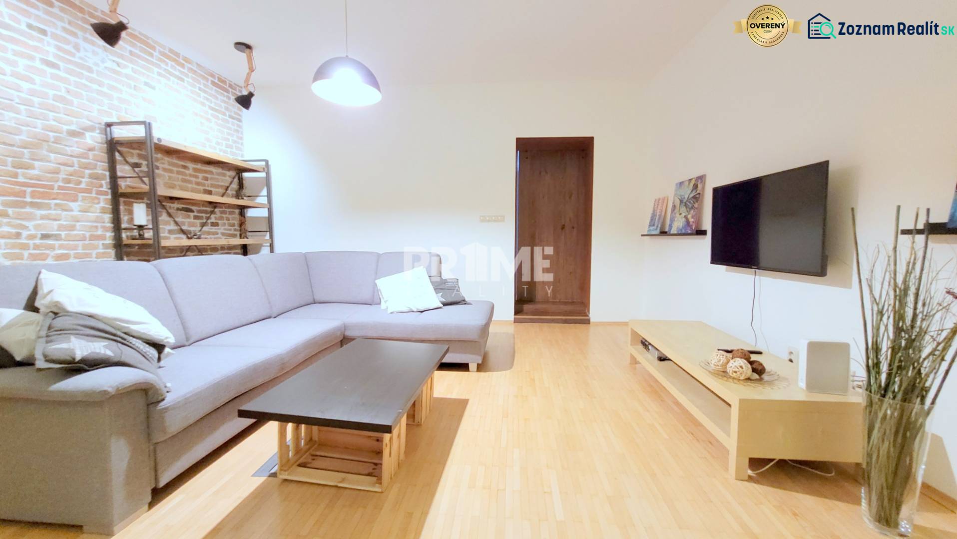 JEDINEČNÝ 2i byt, REKONŠT., 2 X .SAMOST.IZBA, Hviezdoslavovo nám.  - Priestranná obývačka s tehlovou stenou, sedačkou a televízorom na Hviezdoslavovo námestie v 2-izbovom byte.