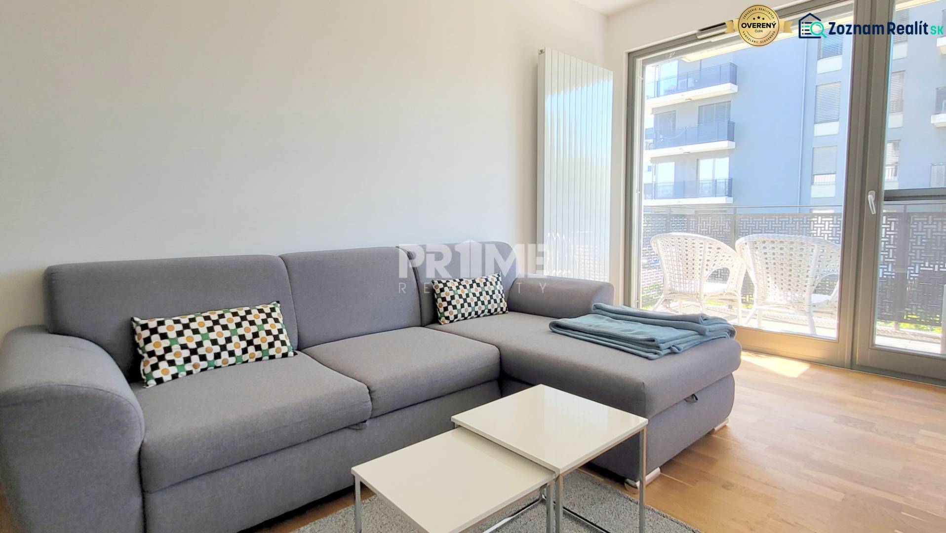 MODERNÝ 3i byt, CUBICON GARDENS, BALKÓN, PARKING, Rudolfa Mocka - Obývacia izba v 3-izbovom byte s pohovkou a balkónom, podlaha s dreveným dekorom.