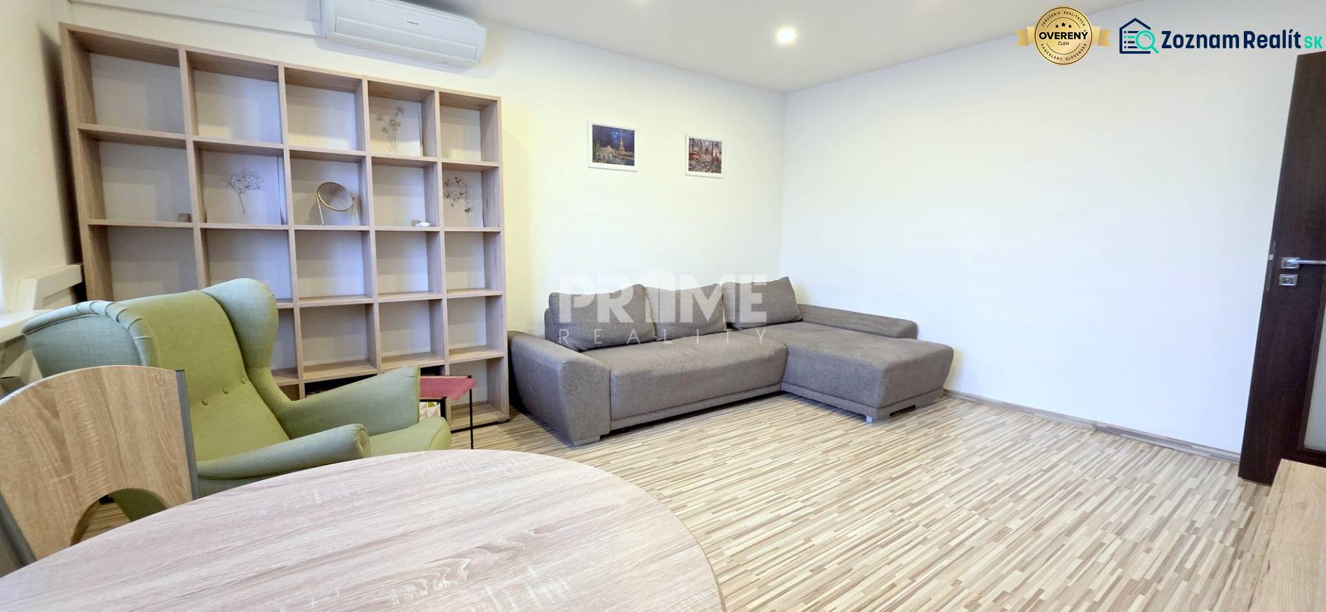 MODERNÝ 2i byt, REKONŠTRUKCIA, KLÍMA, MOZARTOVA ulica, Horský park - Obývačka v 2-izbovom byte s gaučom, kreslom a policovou stenou, podlaha s dreveným dekorom.