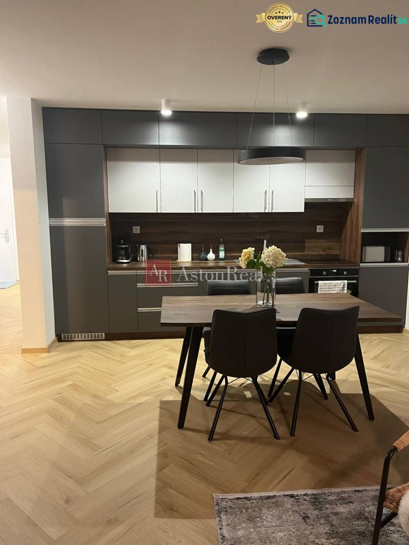 EXKLUZÍVNE-PREDAJ 3-IZBOVÝ BYT POPRAD, širšie centrum 80 m2 s gar.st. - Kuchyňa v 3-izbovom byte so sivými skrinkami a podlahou s dreveným dekorom.