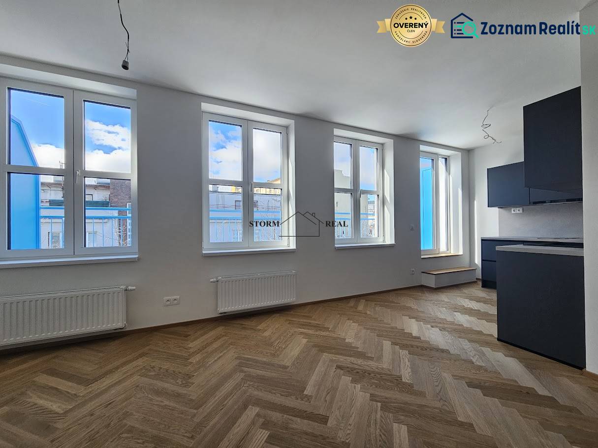 VÝNIMOČNÝ APARTMÁN priamo v centra mesta - projekt UNO Poštová - 1-izbový byt s podlahou s dreveným dekorom a čiernou kuchynskou linkou.