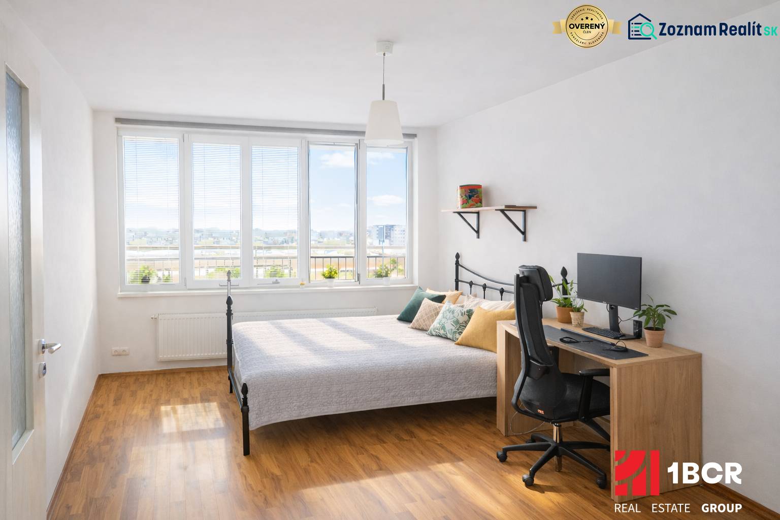 INVESTIČNÉ BÝVANIE V TOP LOKALITE: 2-IZBOVÝ BYT, JÉGÉHO UL, BRATISLAVA - Spálňa v 2-izbovom byte s posteľou, stolom, počítačom a podlahou s dreveným dekorom.