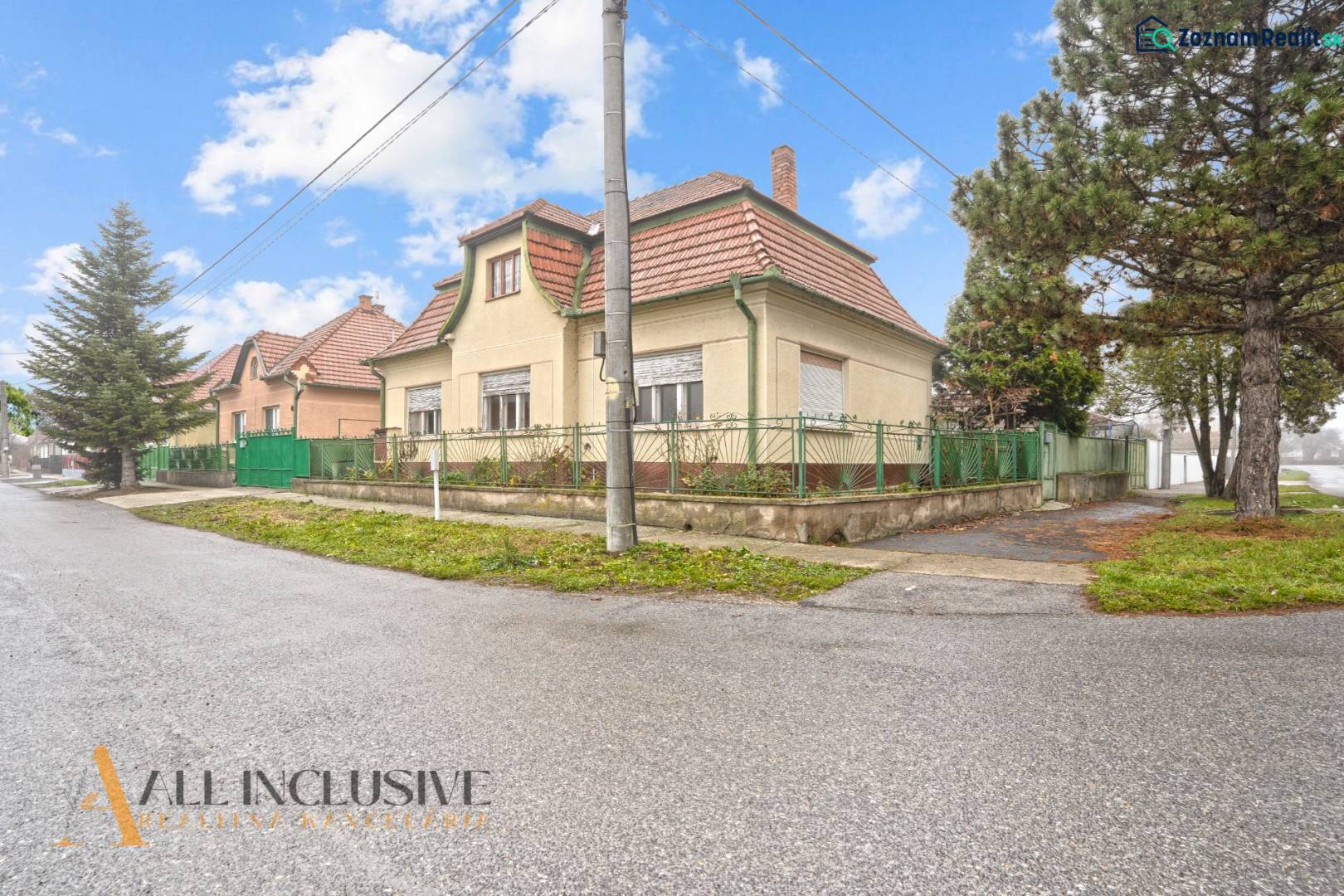 REZERVOVANÉ 4-IZBOVÝ RODINNÝ DOM, TOPOĽNÍKY - Rodinný dom v Topoľníkoch s červenou strechou a vysokým stromom pri ceste.