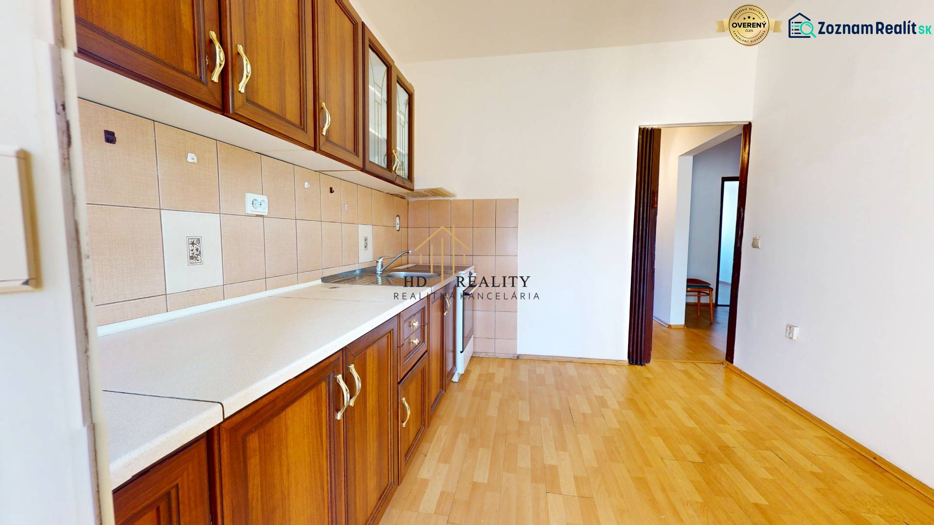 Predaj, trojizbový byt v Kremnici - Kuchyňa v 3-izbovom byte s podlahou s dreveným dekorom a drevenými skrinkami.