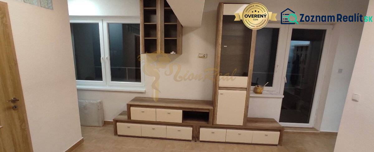 1-izb. byt, Krížná ul., Staré Mesto s veľkou lodžiou - Obývacia izba v 1-izbovom byte s nábytkom, oknom a podlahou s dreveným dekorom.