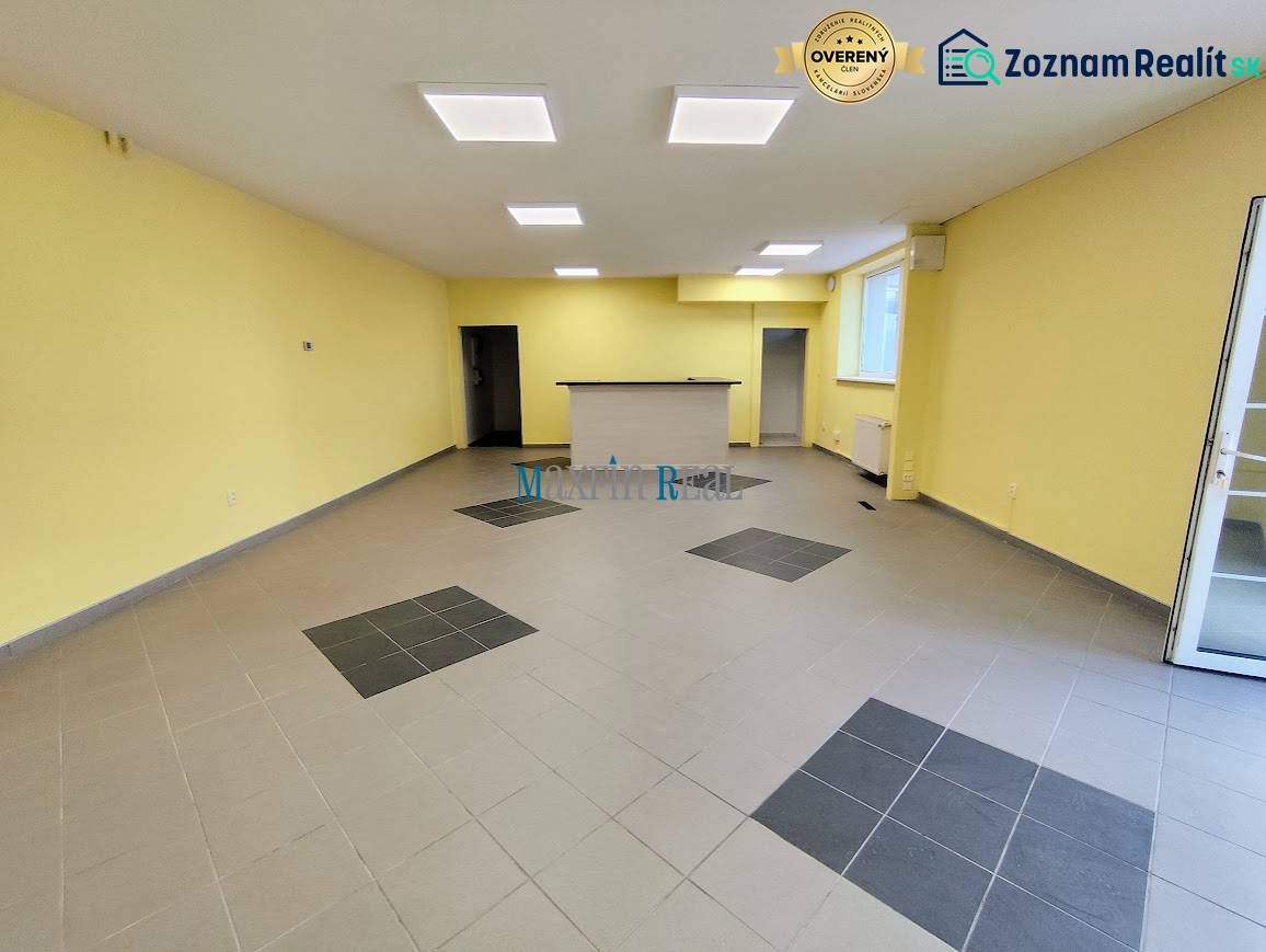 Obchodný priestor v Nitre s parkovaním - Interiér obchodných priestorov s dlažbou a recepciou, osvetlený stropnými svetlami.
