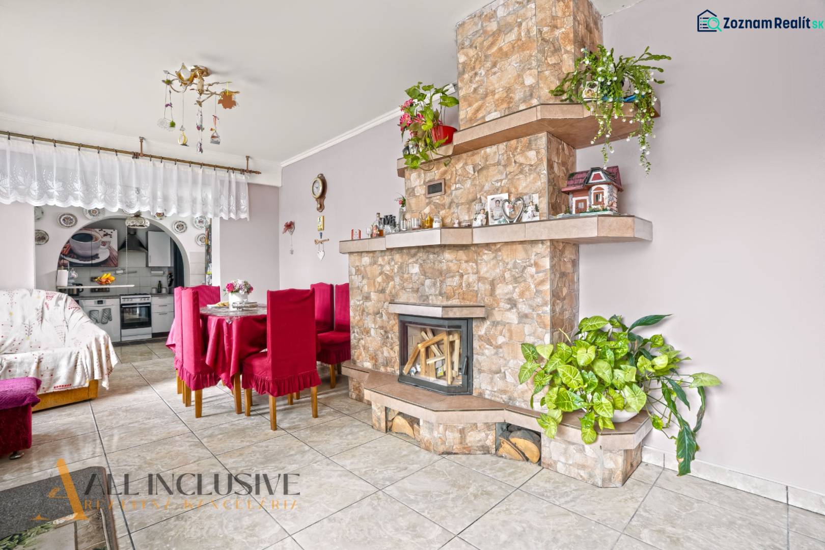 NA PREDAJ 5-IZBOVÝ RODINNÝ DOM NA 15Á POZEMKU,ŠALGOČKA - Obývacia izba v rodinnom dome s krbom, jedálenským stolom a dekoráciami.