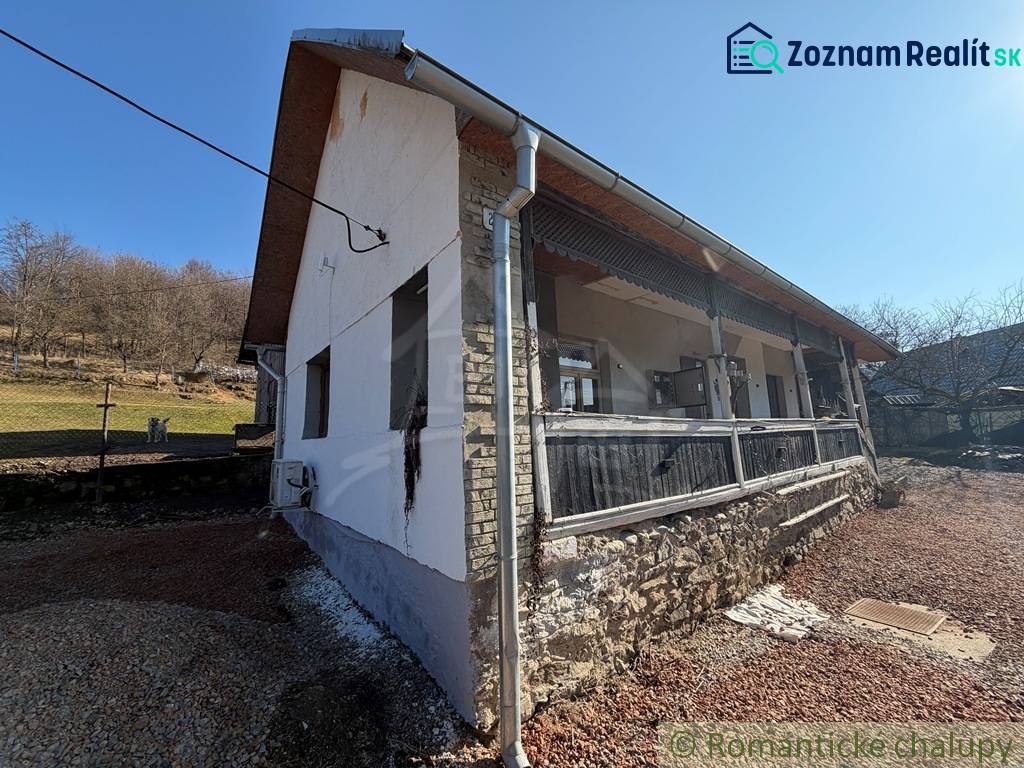 Štýlová chalupa v horskej dedinke Ratkovské Bystré - Exteriér rodinného domu v Ratkovskom Bystrom so slnečným počasím a kamennou základňou.