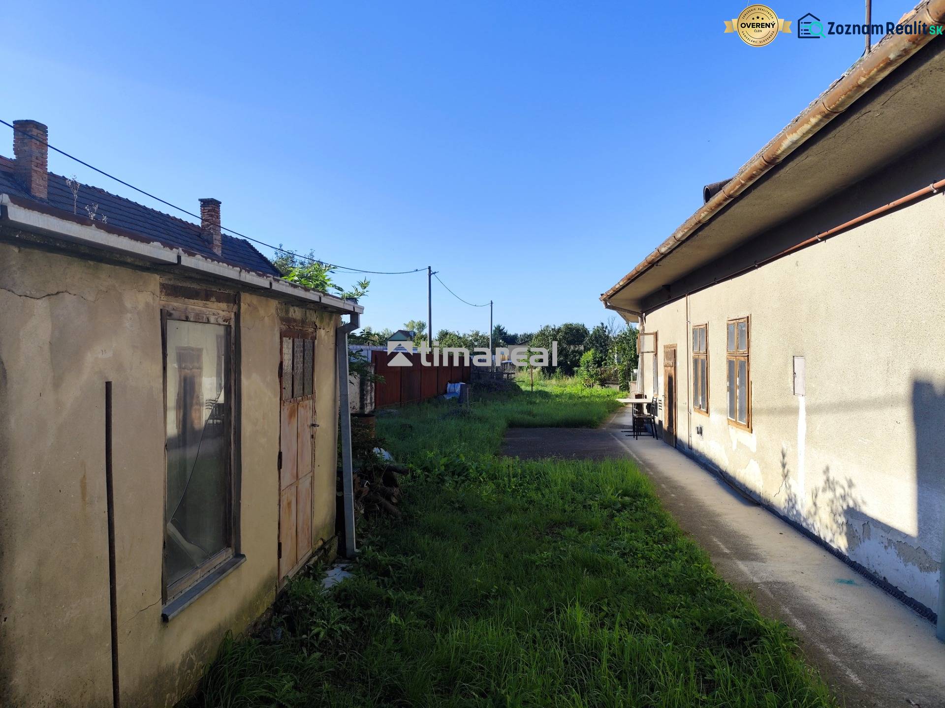 Starší dom neďaleko Slnečných jazier v obci Réca - Dvor medzi budovami v rodinnom dome v obci Reca s chodníkom a trávnatou plochou.