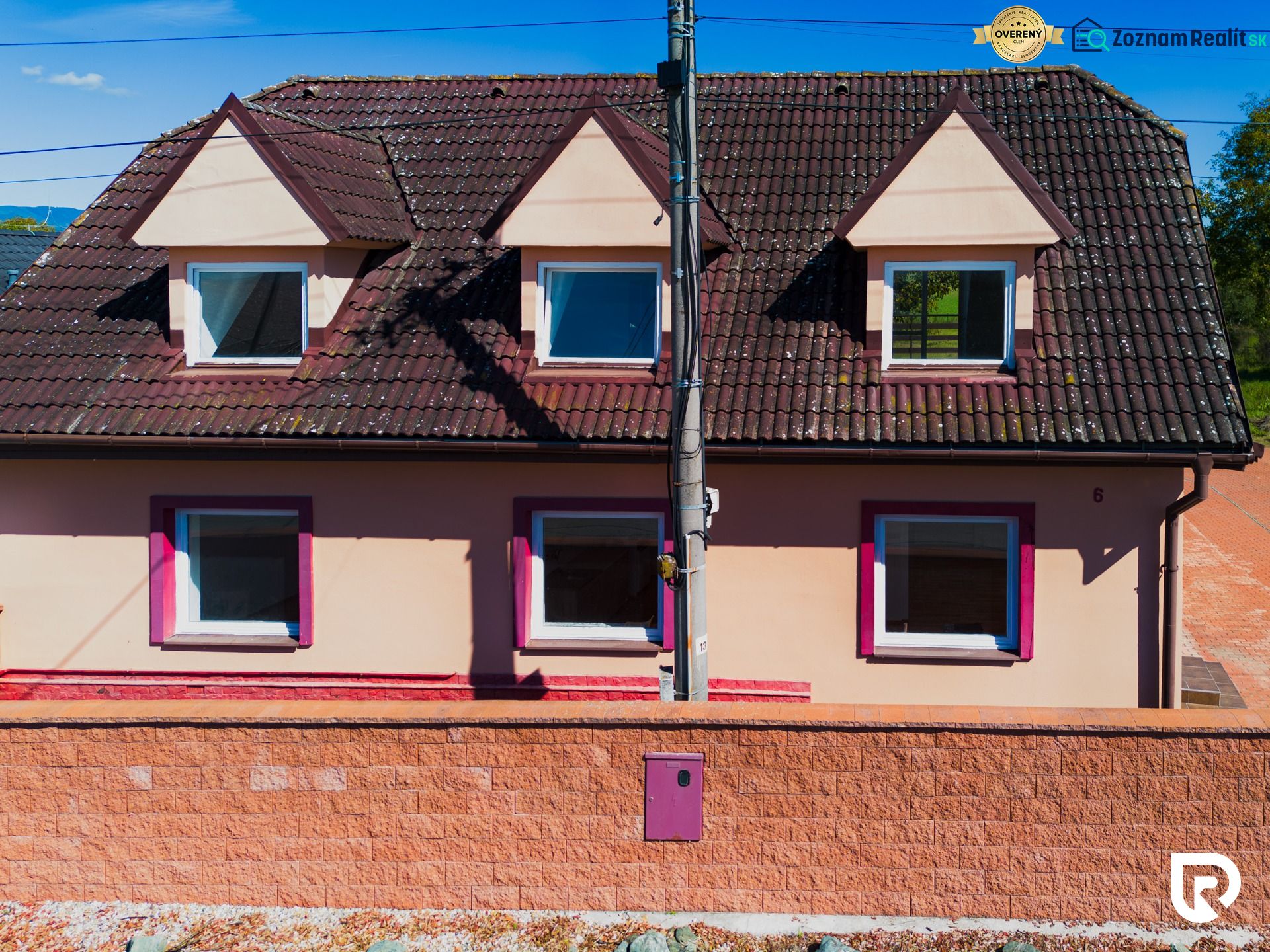 6-izbový rodinný dom s pozemkom 2218m2  | Horňany - Rodinný dom v Horňanoch s červenou strechou a omietkou v odtieni ružovej.