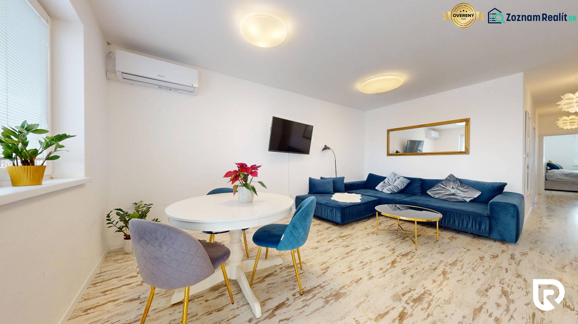 4-izbový byt 92m2 + terasa 14m2 | Bernolákovo - Obývačka v 4-izbovom byte s modrou sedačkou, podlahou s dreveným dekorom a izbovými rastlinami.