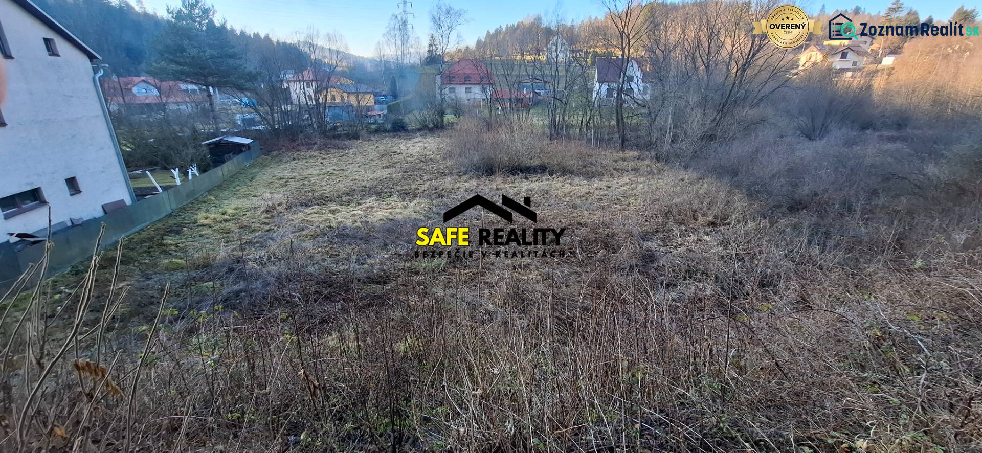 Stavebný pozemok Svrčinovec - Pozemok na bývanie v Svrčinovci obklopený stromami a blízke domy v pozadí.
