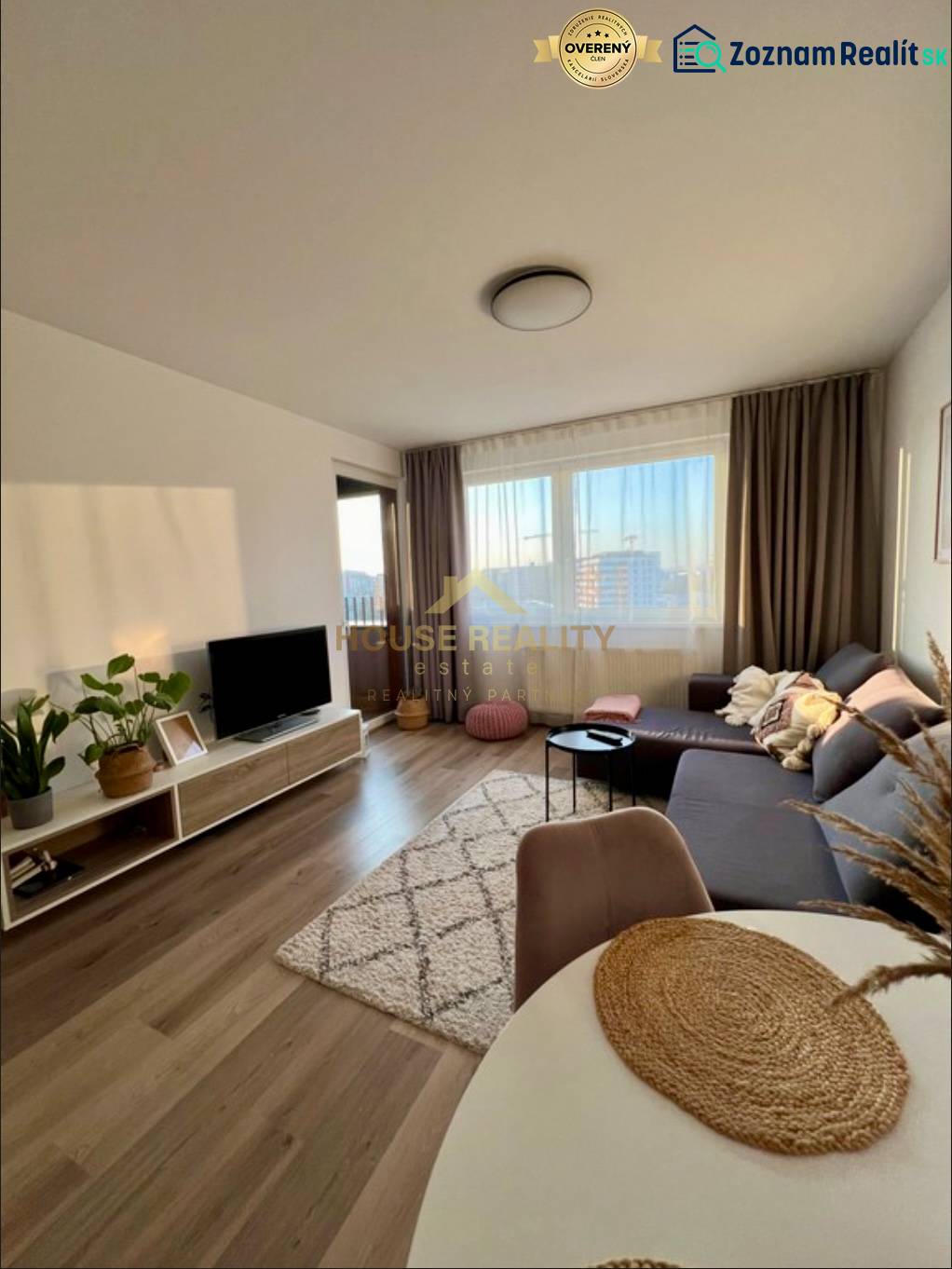 Novostavba FUXOVA 2 izbový byt, parking, Bosákova ul., BA V. Petržalka - Obývacia izba so sedačkou, televízorom a podlahou s dreveným dekorom v 2-izbovom byte.