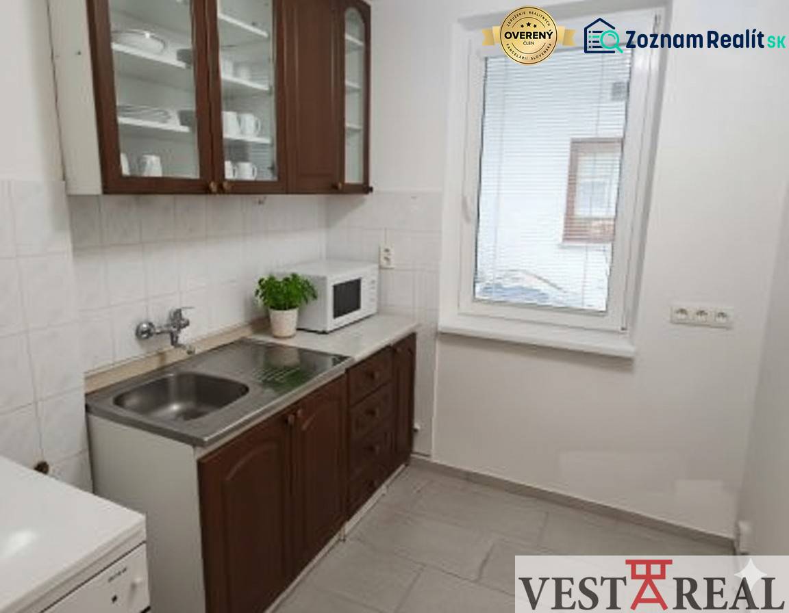 Na predaj: 2-izbový byt v centre mesta Galanta – časť Nová Doba - Kuchyňa 2-izbového bytu s tmavým nábytkom, spotrebičmi a svetlou dlažbou.