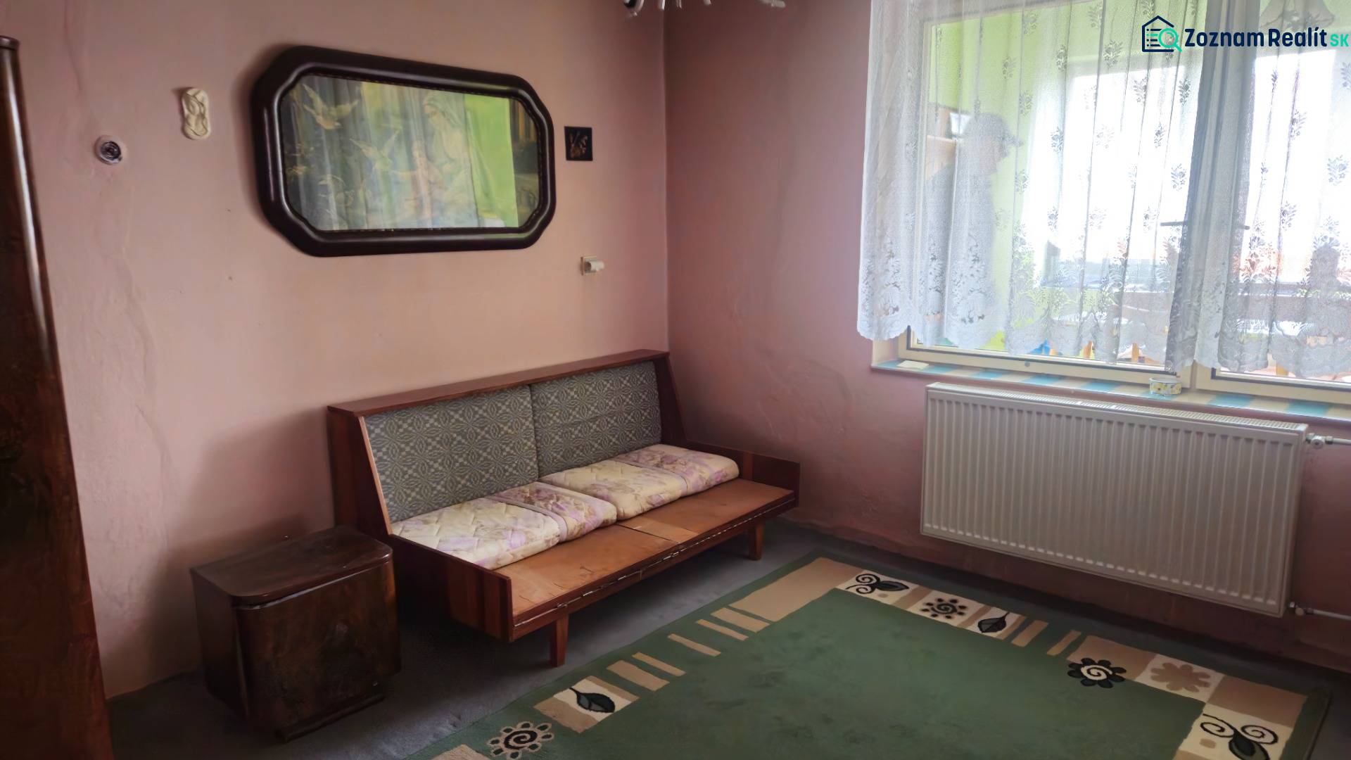 Predaj 4 izbový rodinný dom Šulekovo  - Izba v rodinnom dome s pohovkou, zeleným kobercom a ornamentálnou záclonou.