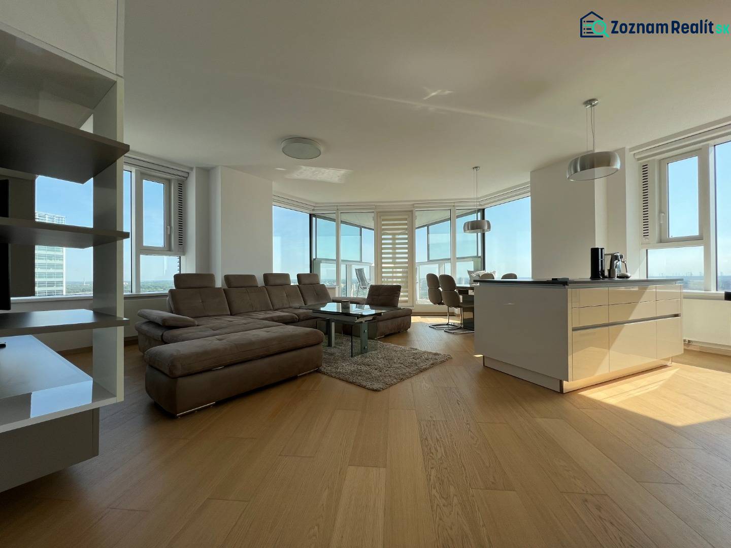 NUERA︱PANORAMA CITY- Veľký 3-izbový byt s výhľadom na hrad - Svetlý 3-izbový byt s podlahou s dreveným dekorom, veľkými oknami a priestrannou sedacou súpravou.