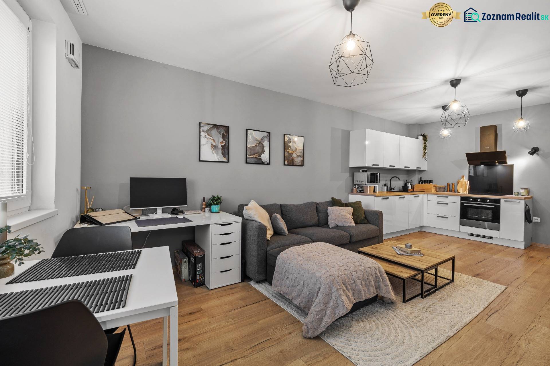 I Na predaj priestranný 2-izbový byt v Rovinke (City Park) - Obývacia izba v 2-izbovom byte s kuchyňou, rozkladacím gaučom a podlahou s dreveným dekorom.