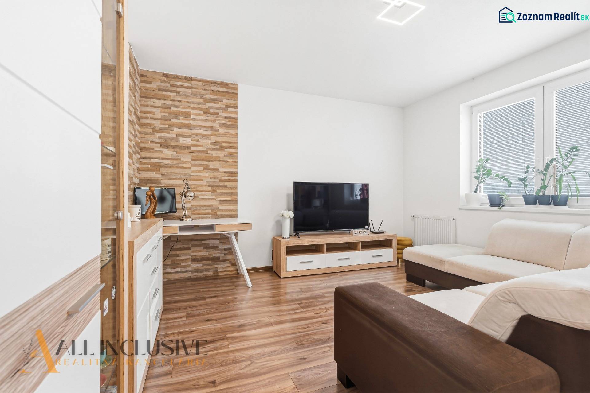 Na predaj moderný 2-izb. byt s loggiou vo Vrábľoch - Obývacia izba s podlahou s dreveným dekorom, TV a krémovou sedačkou v 2-izbovom byte.