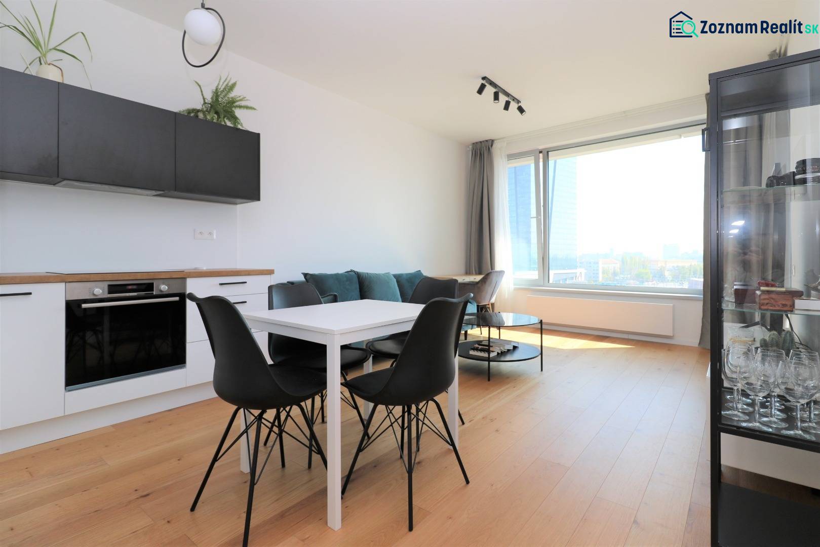 NUERA︱SKY PARK Moderný 2-izbový byt na 6. poschodí, veža 3 - Kuchyňa a jedálenský stôl s čiernymi stoličkami v 2-izbovom byte s podlahou s dreveným dekorom.