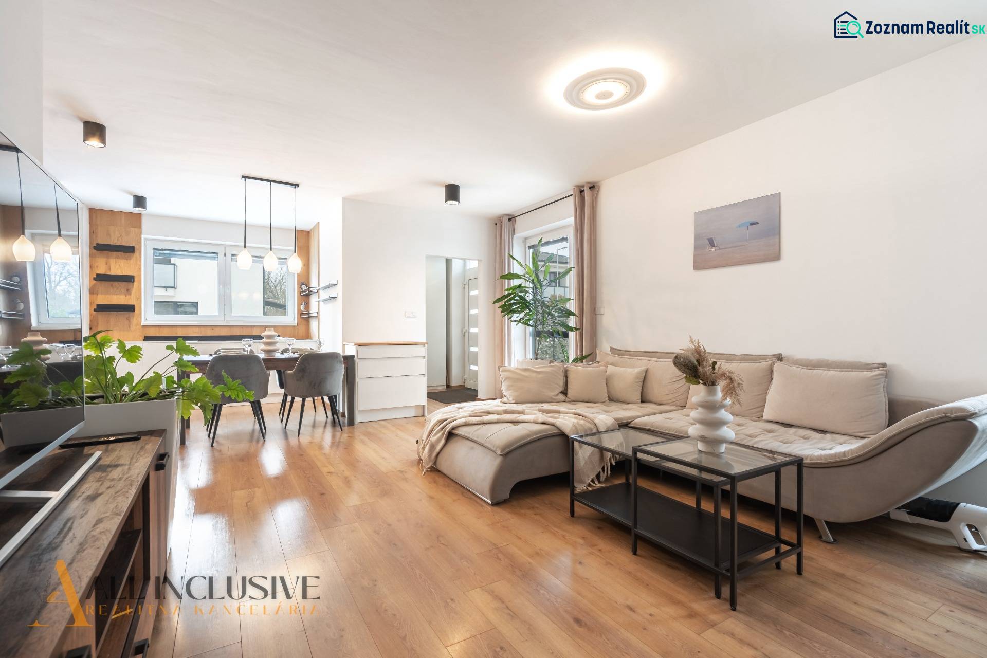 Rezervované 3-izbový byt so záhradou, Šamorín - Obývačka v 3-izbovom byte s pohovkou, jedálenským stolom a podlahou s dreveným dekorom.