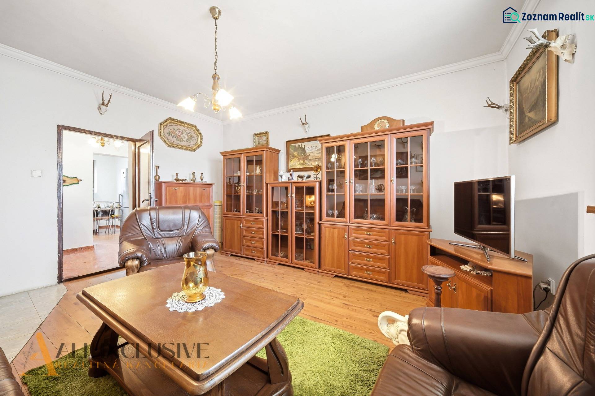Na predaj 3-izbový rodinný dom, Topoľníky - Obývacia izba v rodinnom dome so skrinkami, kreslami a podlahou s dreveným dekorom.