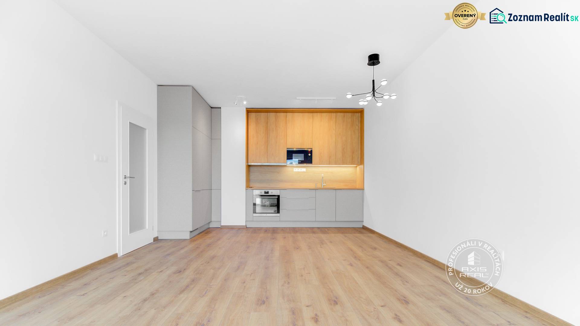  2-izbový byt, NOVÝ, veľkorysý ÚLOŽNÝ PRIESTOR, PARKOVANIE - Svetlá kuchyňa v 2-izbovom byte s podlahou s dreveným dekorom a bielymi stenami.