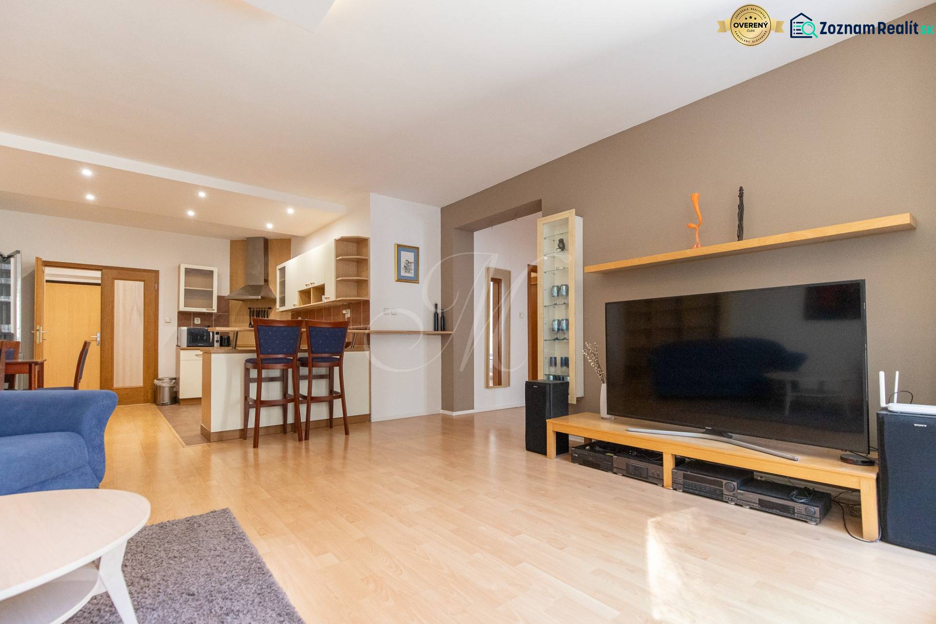 Priestranný 3-izbový byt s loggiou, Staré Mesto - Obývacia izba v 3-izbovom byte so zariadením a podlahou s dreveným dekorom.