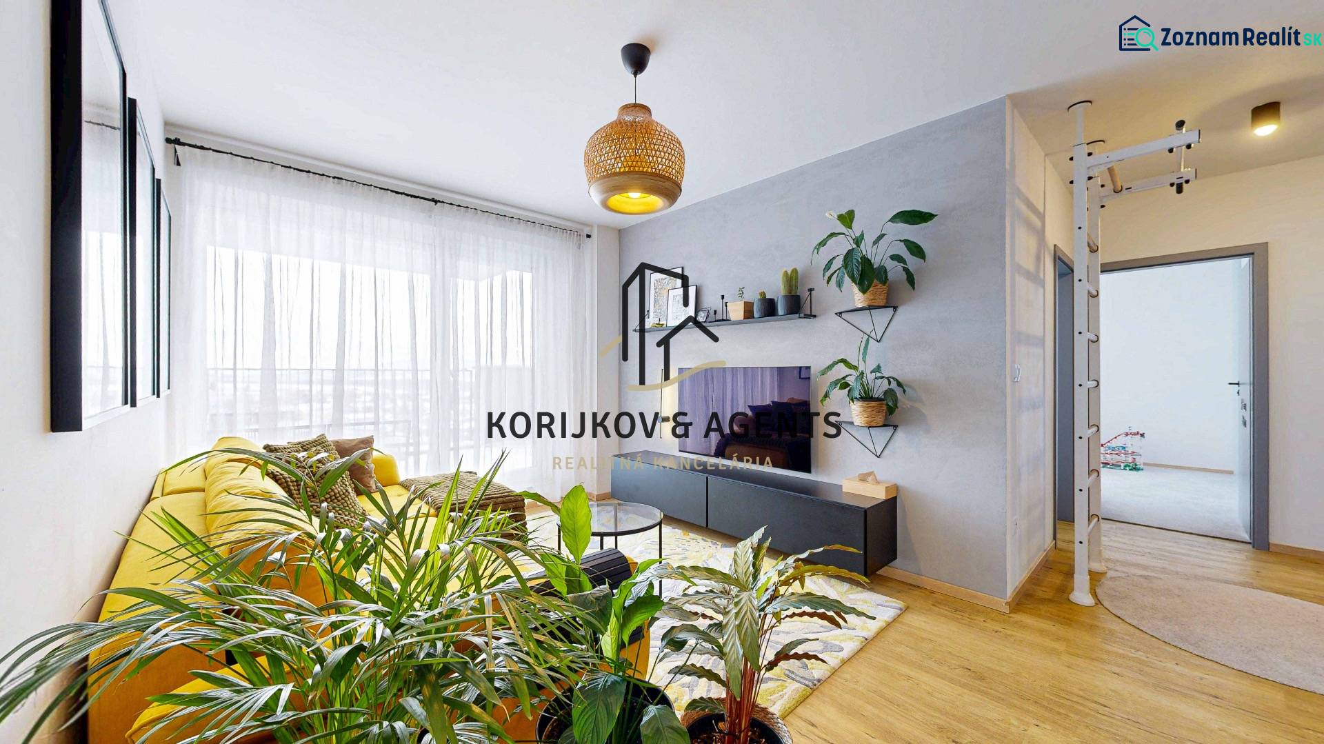 PREDAJ, 3izb. zariadený byt, novostavba Zelená stráň, Košická Nová Ves - Obývačka v 3-izbovom byte s veľkou žltou sedačkou a rastlinami, podlaha s dreveným dekorom.
