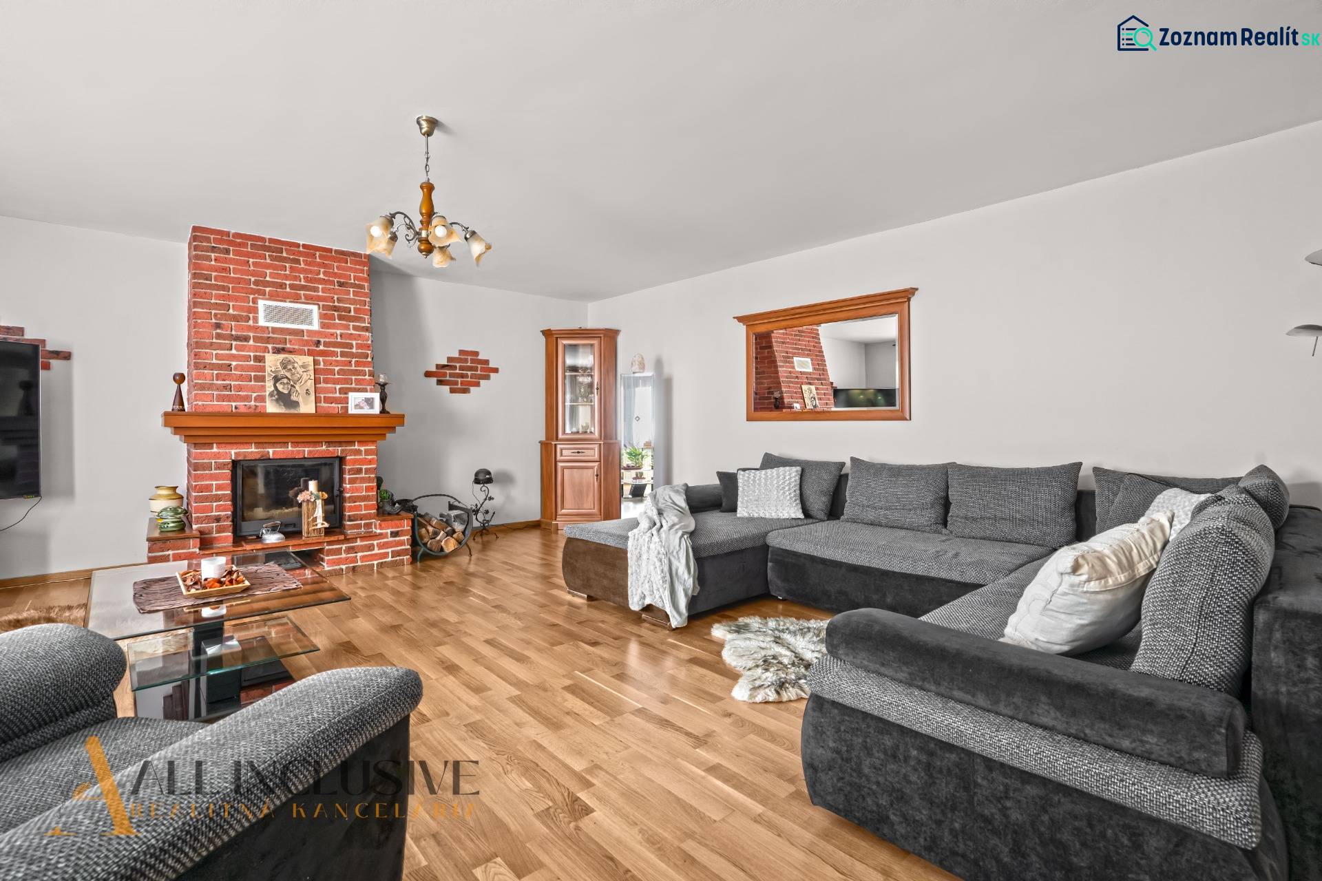 NA PREDAJ 6-IZBOVÝ POSCH. RODINNÝ DOM, HORNÉ SALIBY - Obývacia izba v rodinnom dome s krbom, šedým gaučom a podlahou s dreveným dekorom.