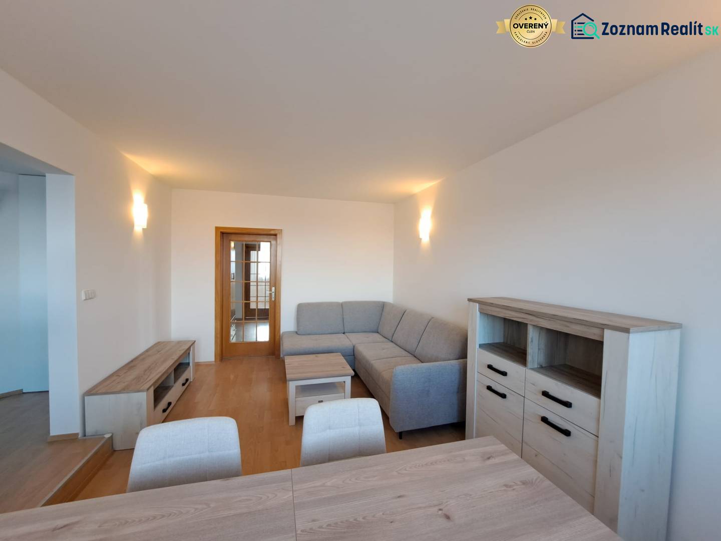 Prenájom pekného a priestranného 4-izbového bytu vo Svite - Obývacia izba v 4-izbovom byte s podlahou s dreveným dekorom a sivou sedačkou.