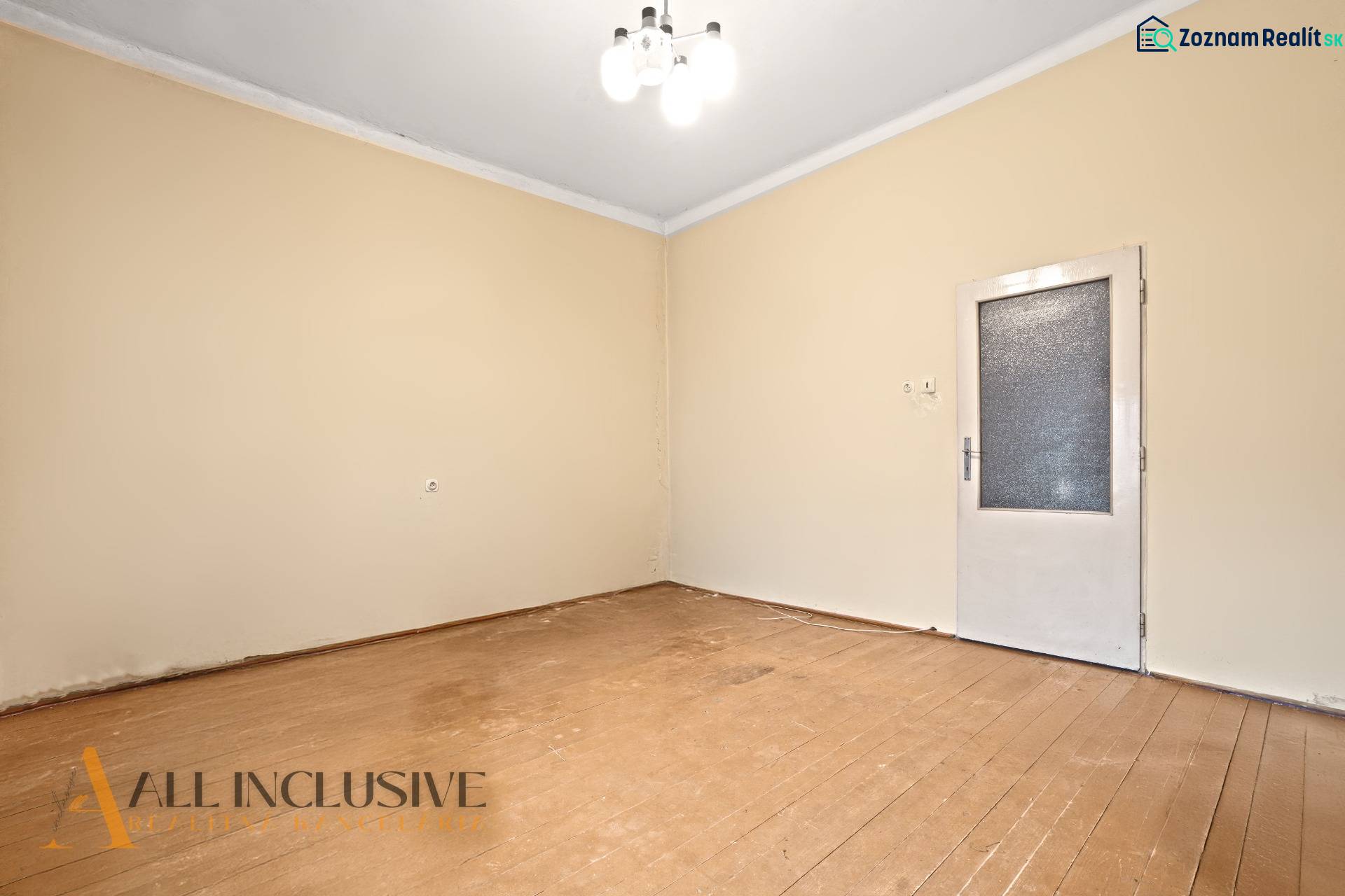 NA PREDAJ 4-IZBOVÝ RODINNÝ DOM V OBCI MOSTOVÁ - Izba v rodinnom dome s podlahou s dreveným dekorom a jednoduchým osvetlením.