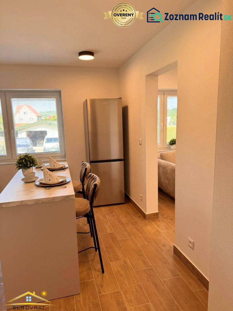 Prenájom: 2 izbový byt v obci Staškov (316-B) - Kuchyňa v 2-izbovom byte s barom, podlahou s dreveným dekorom a chladničkou.