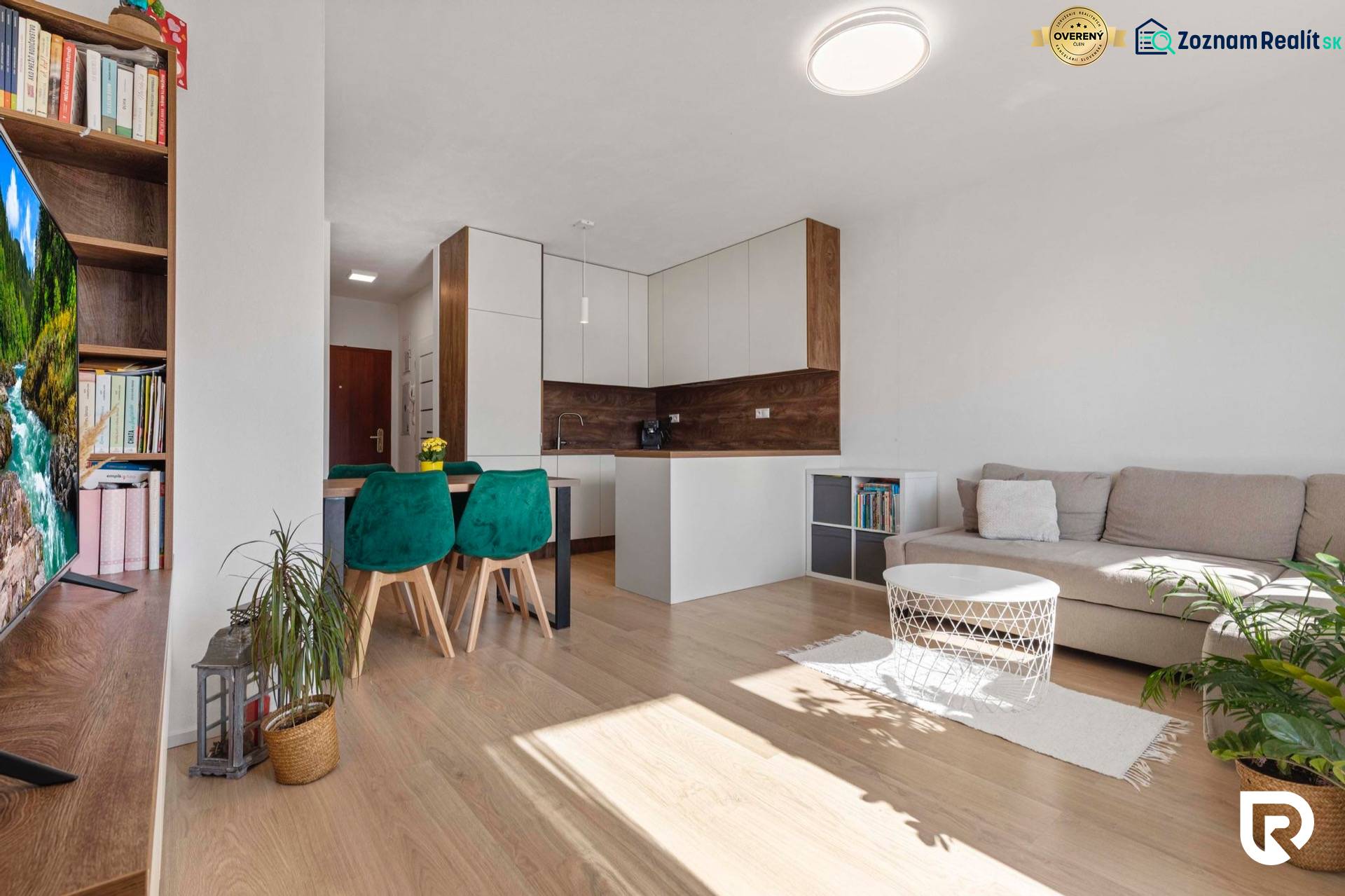 | Krásny a moderný 2-izbový byt | 51,50m² | - Obývacia izba s kuchyňou v 2-izbovom byte, podlaha s dreveným dekorom, zelenými stoličkami.