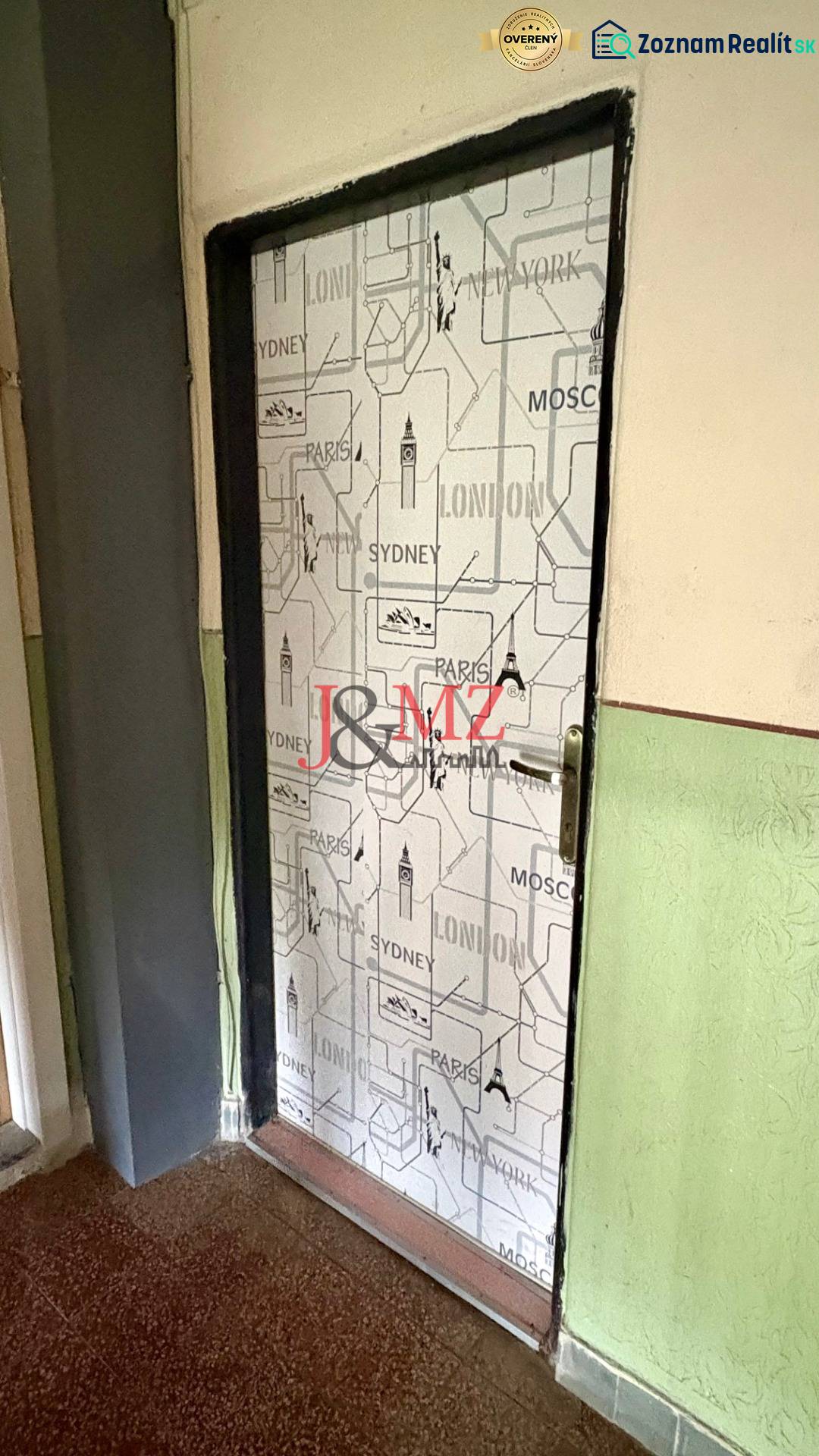 Predaj garsónky – Tlmače, Lipník- ihneď voľná (MK-3) - Dvere pokryté mestským motívom, podlaha s dreveným dekorom, stena v sýtozelenej farbe.