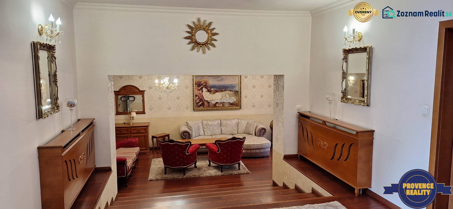 Luxusný rodinný dom s bazénom a dvojgarážou v Komárne - Luxusný interiér rodinného domu s dreveným dekorom, pohovkou a umeleckými dielami na stenách.