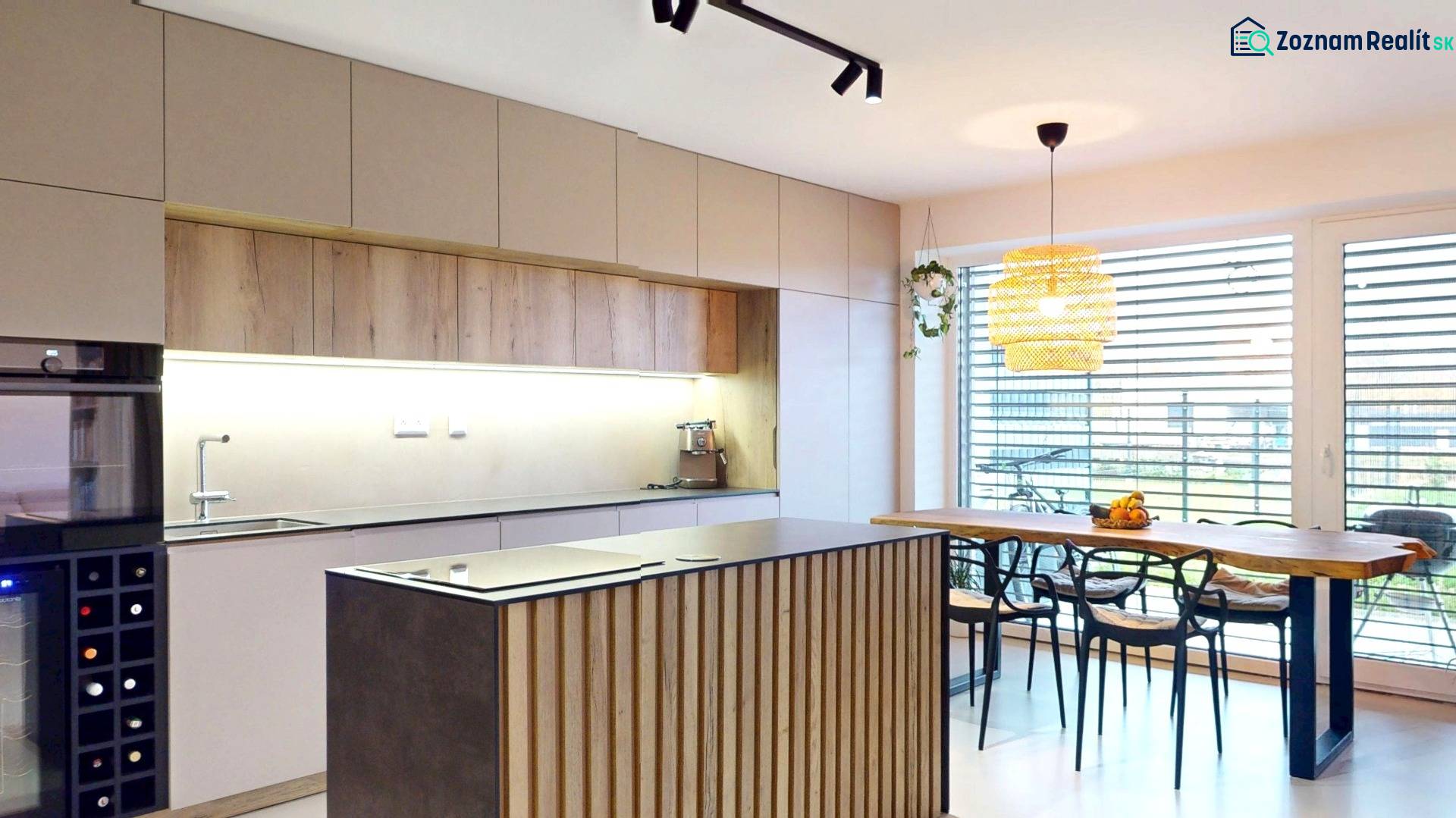 Novozariadený rodinný dom s veľkými spálňami i šatníkom pri Trenčíne   - Kuchyňa v rodinnom dome s dreveným dekorom nábytku a veľkými oknami.