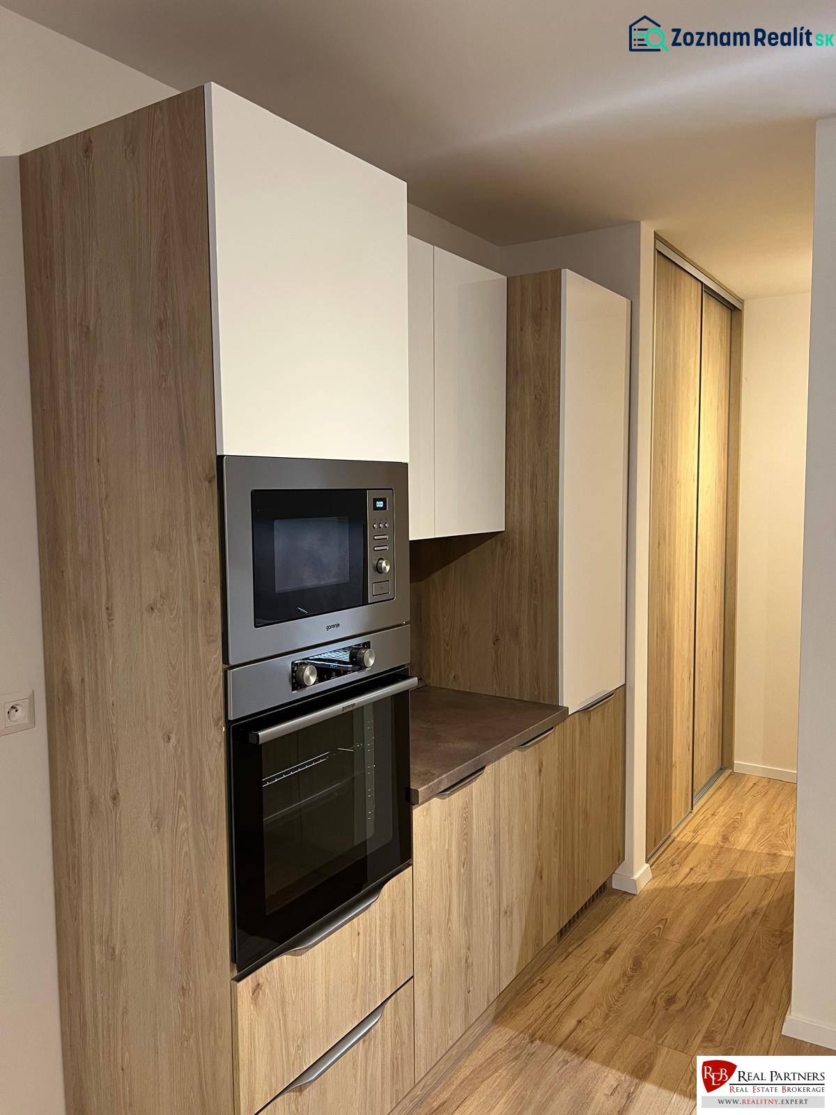 - PRENÁJOM 2-IZ. BYTU S PARKOVACÍM MIESTOM – MILOSLAVOV - Kuchynská časť dvojizbového bytu s podlahou s dreveným dekorom a vstavanými skrinkami.